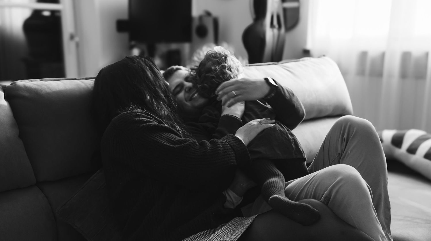 Intima fotografia in bianco e nero che mostra un momento tenero di una famiglia su un divano.