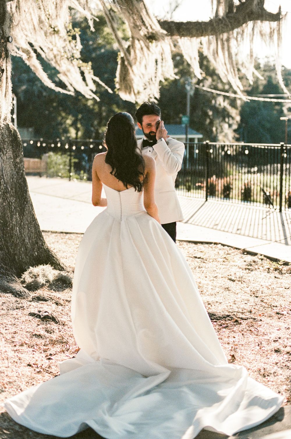 A flowing white wedding dress twirls gracefully in a romantic outdoor setting with string lights and trees.