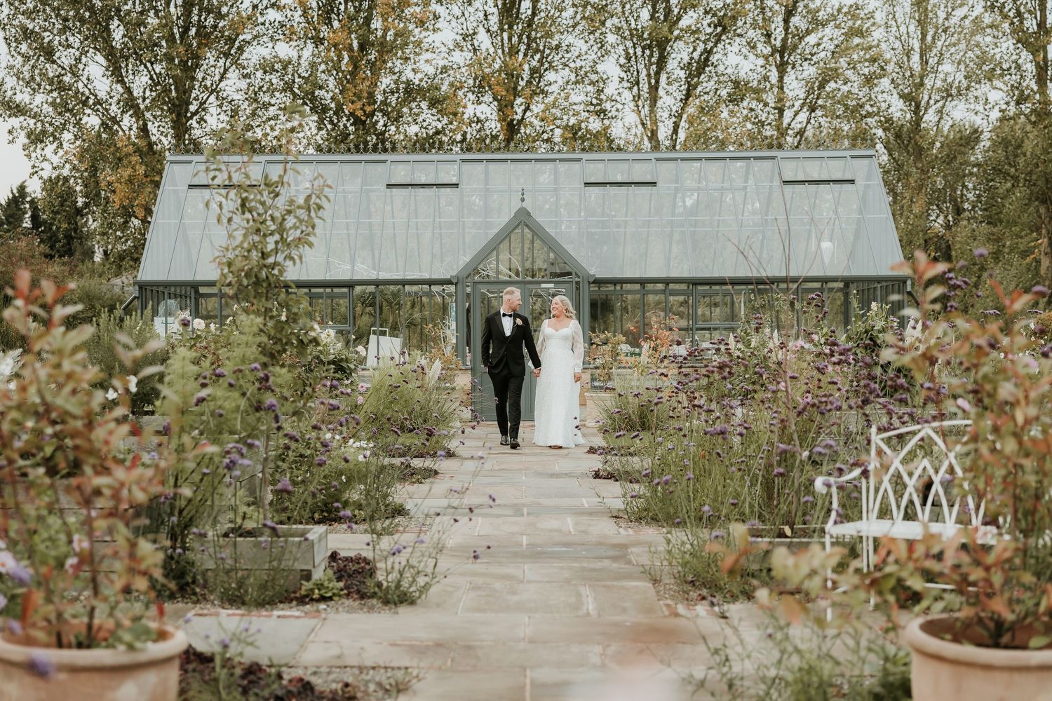 Romantic wedding couple embracing at Middleton lodge, walled garden wedding. Feather wedding dress and blue suit.