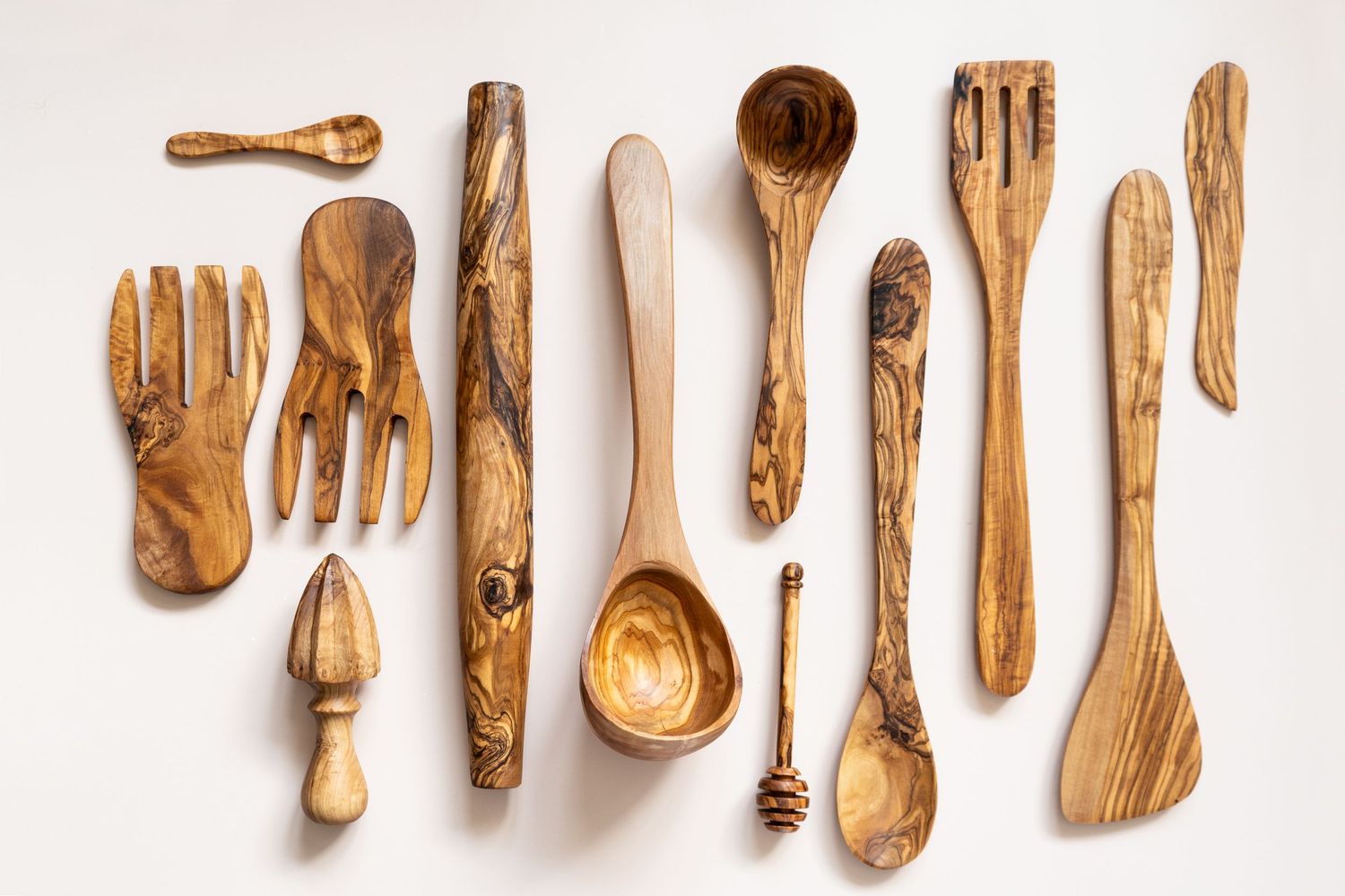 a flat lay of several handcrafted wooden utensils on a pale pink backdrop