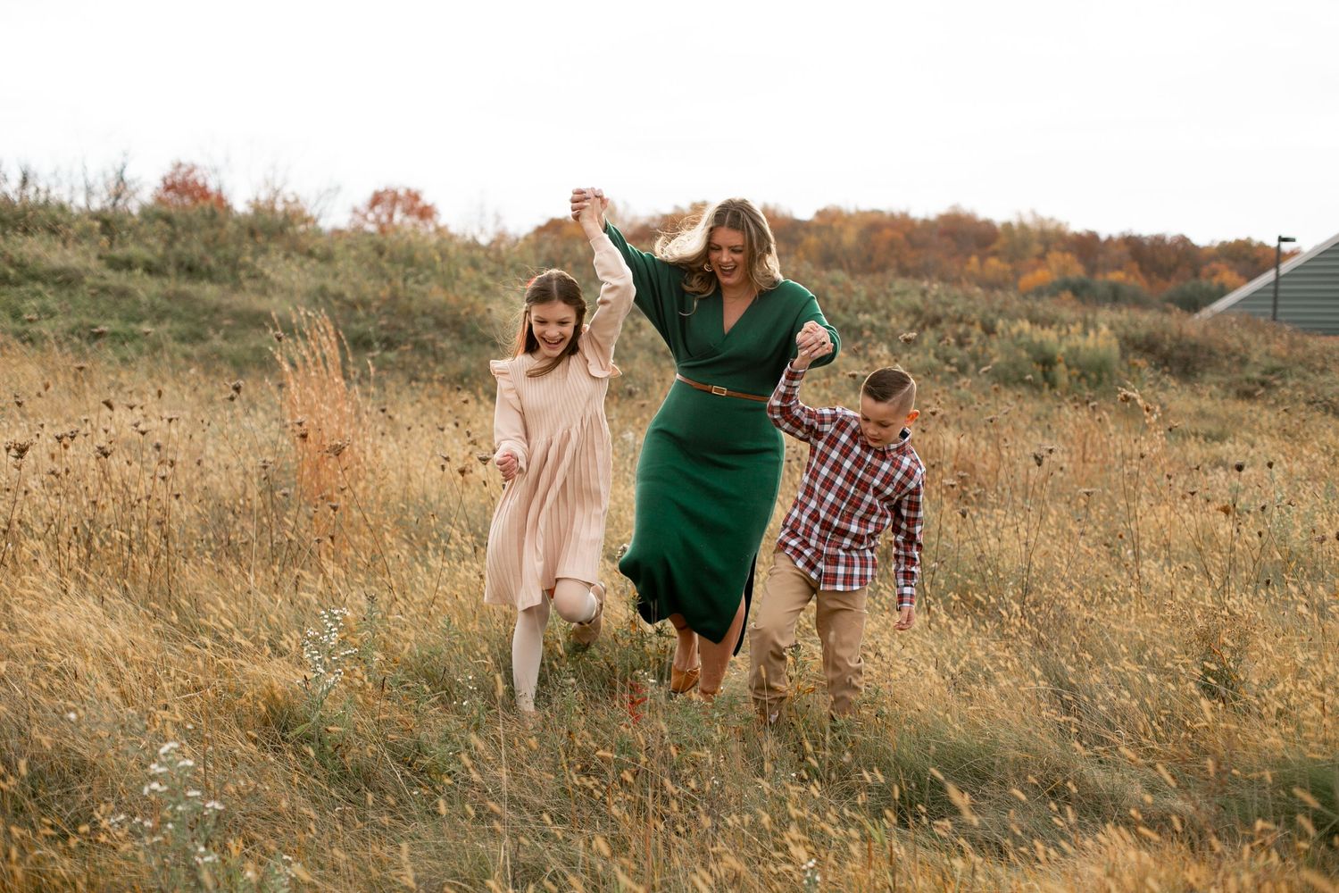 A family walks together through a golden autumn field during sunset.