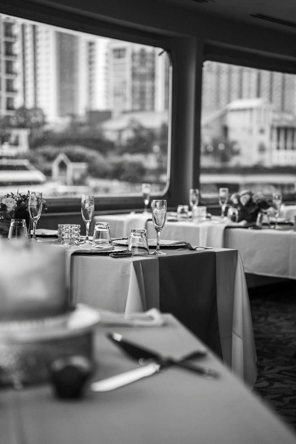 Elegant restaurant dining tables set with wine glasses and white linens in a modern upscale setting. Micro wedding on Yacht StarShip in Tamp