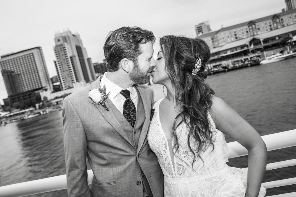 A couple shares a romantic kiss on a boat dock with a waterfront cityscape in the background. Micro wedding on Yacht StarShip in Tampa