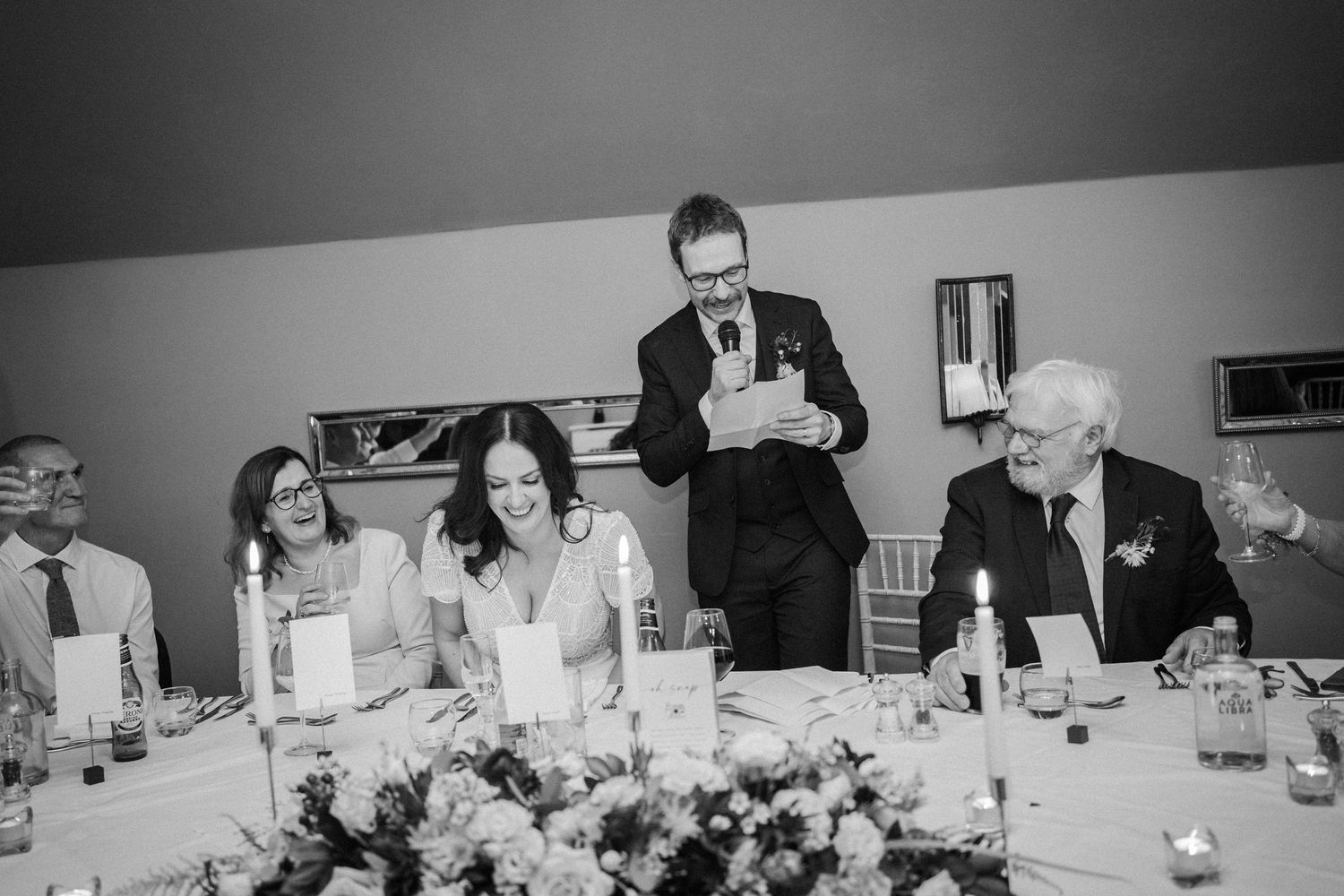 Black and white panoramic photo of business professionals seated around a conference table during a meeting.