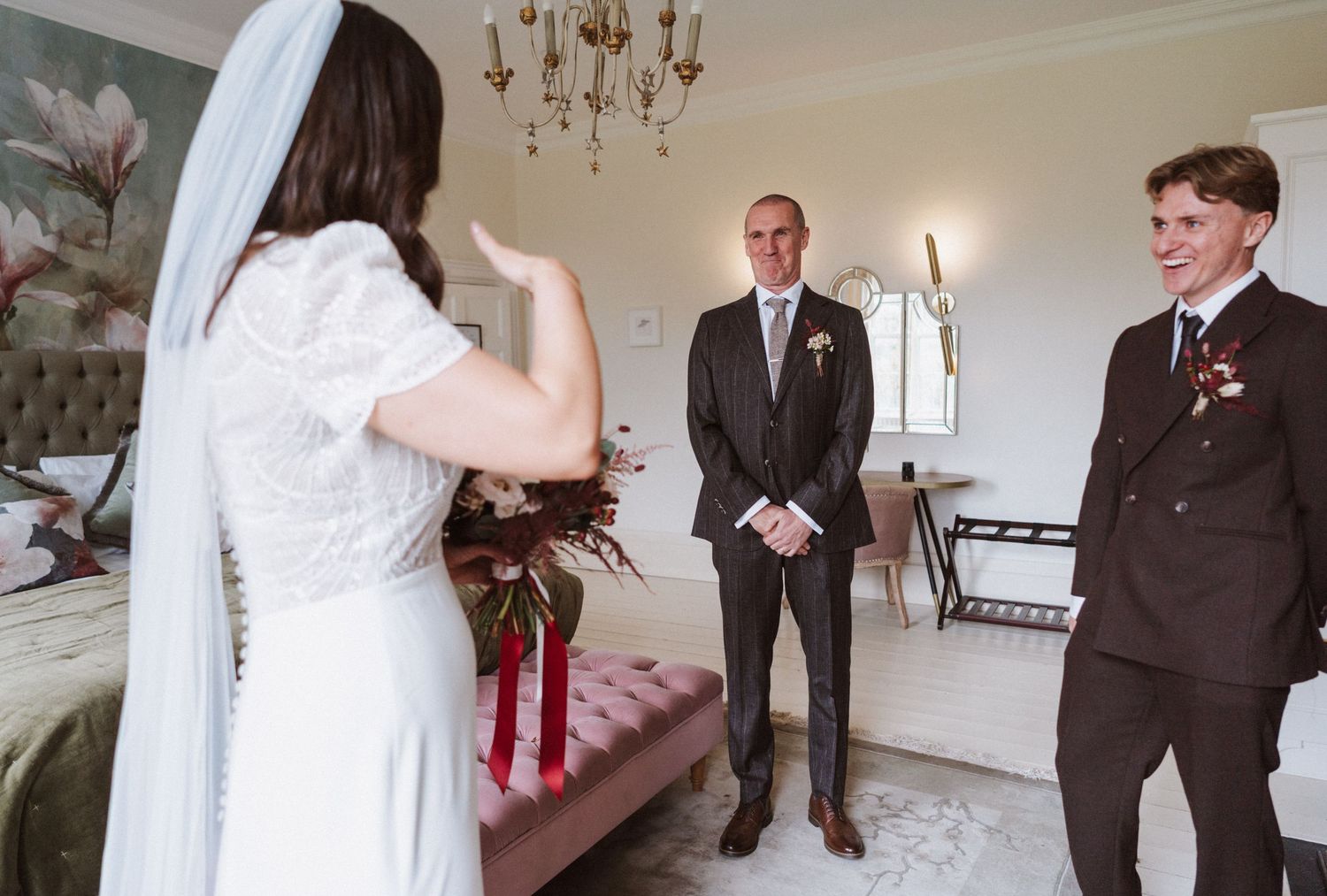 Wedding party members in formal attire standing in an elegant indoor venue.