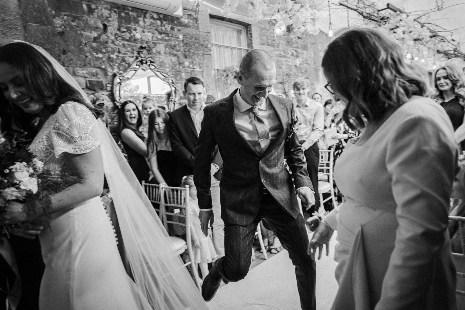 Wedding celebration in a rustic stone venue with guests mingling and dancing together.