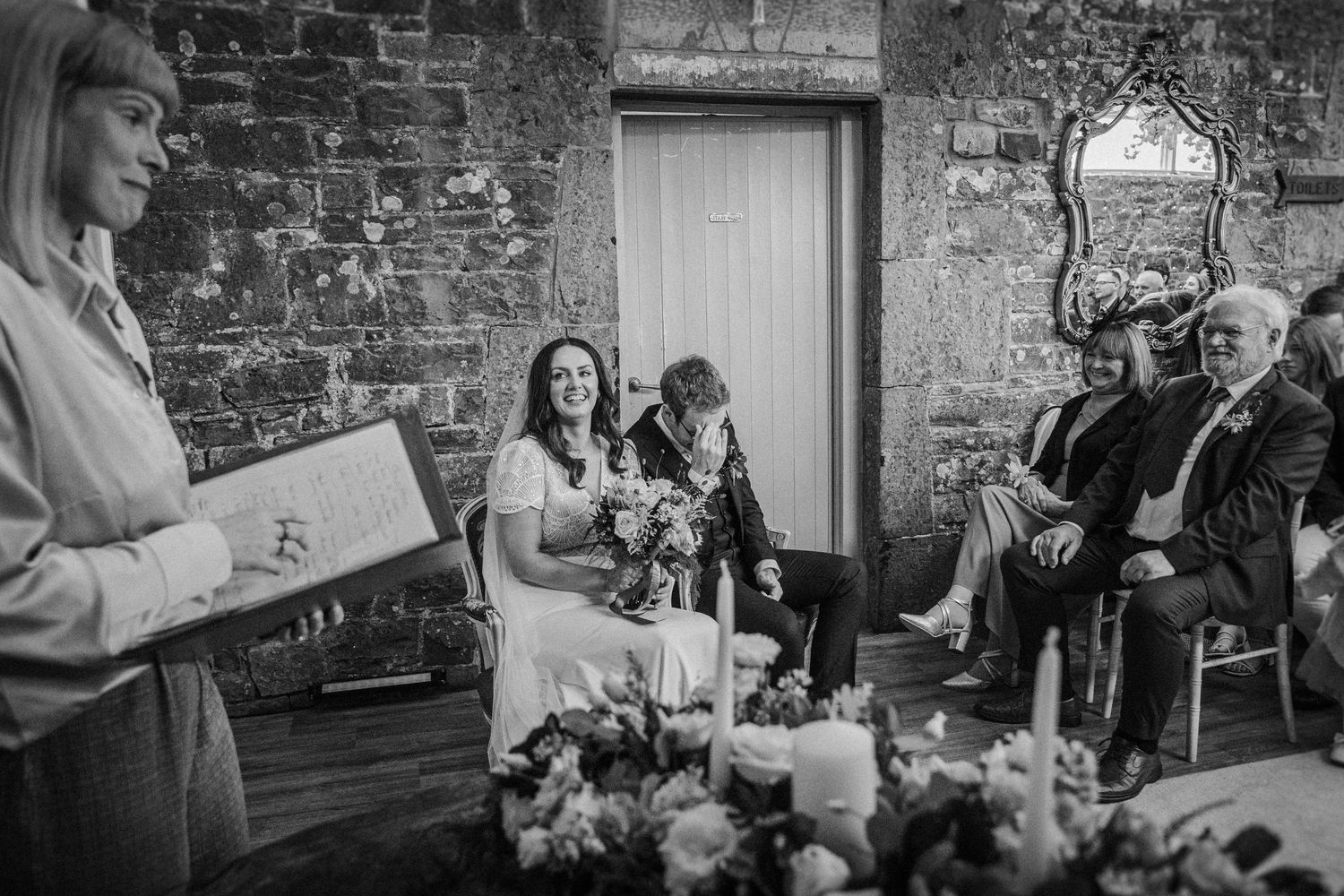 Reception party in a charming stone-walled venue with guests gathered around tables.