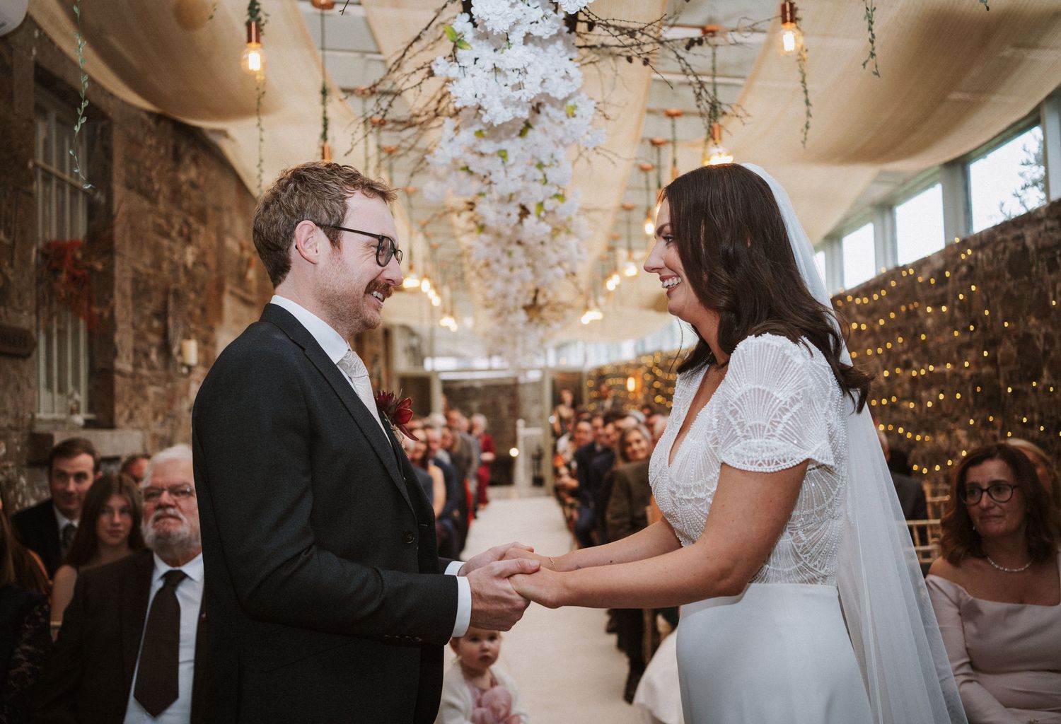 Wedding celebration in an ornate room with hanging lights and romantic ambiance.