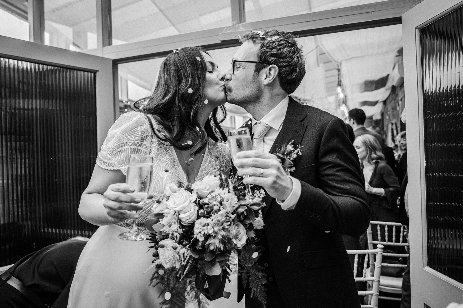 Wedding reception scene with guests toasting and celebrating at decorated indoor venue.
