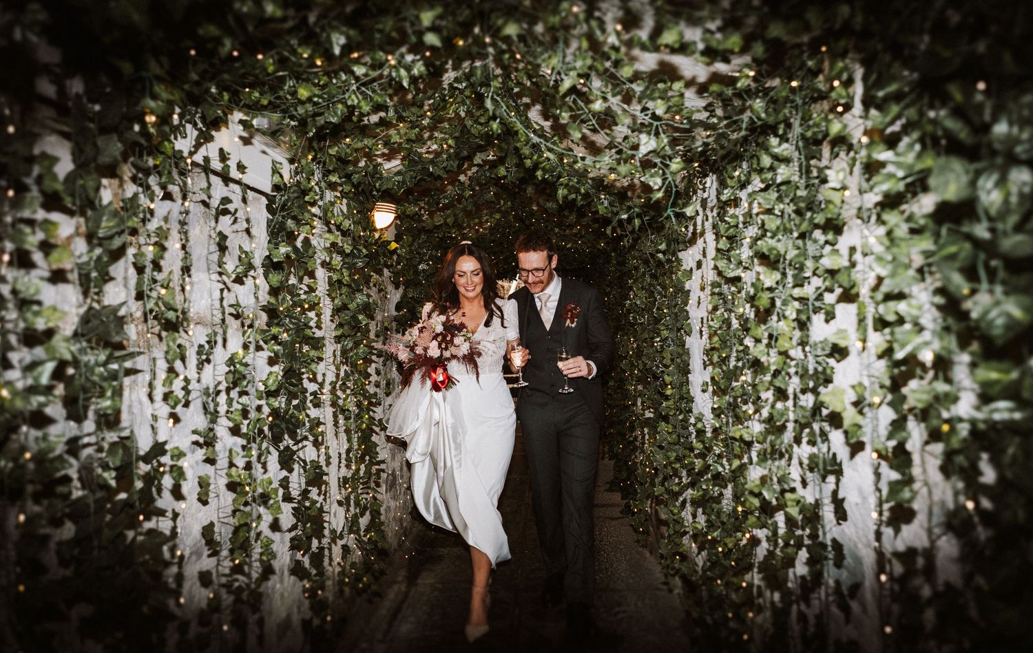 Elegant wedding reception setup with hanging greenery and string lights creating a romantic atmosphere.
