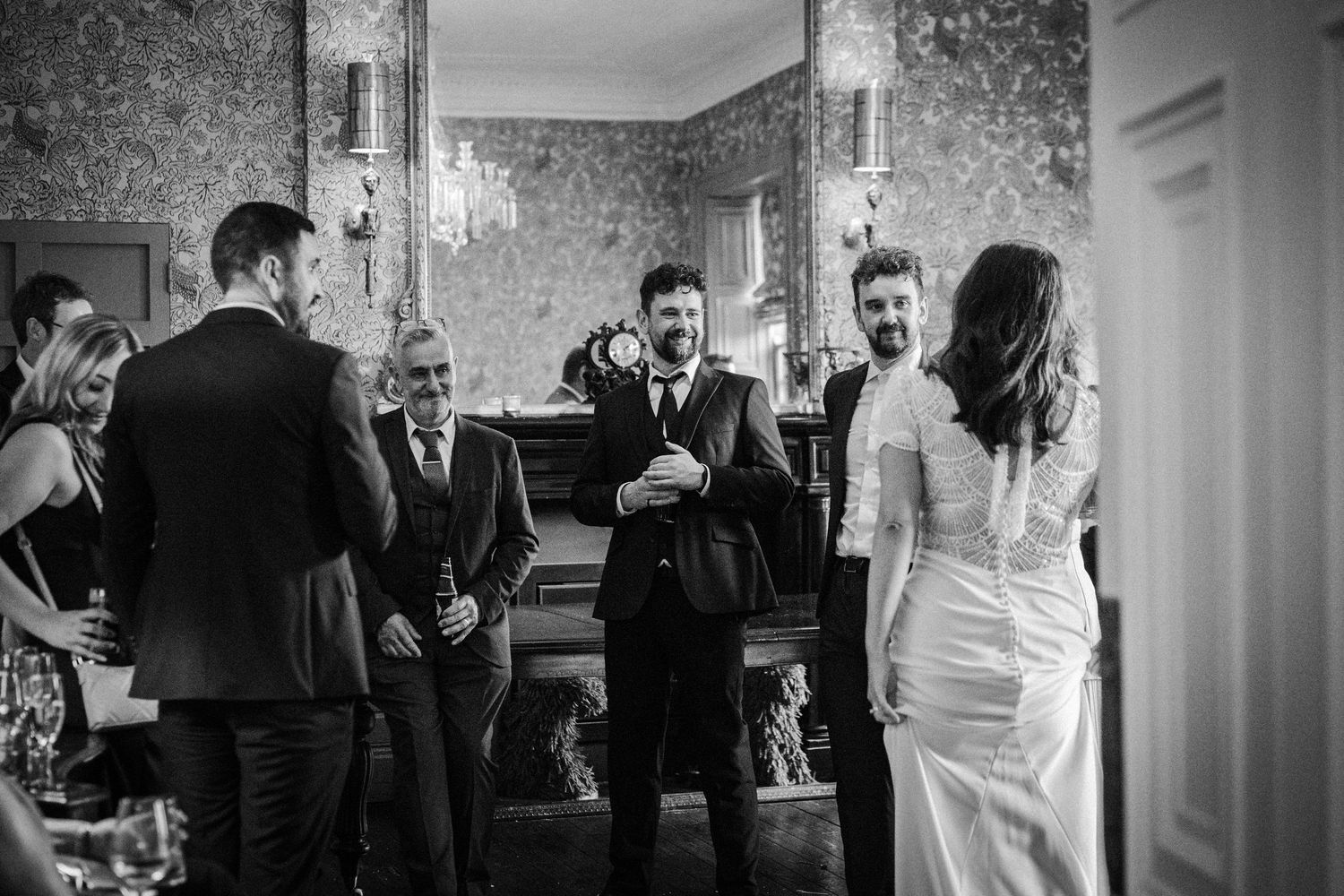 A black and white wedding reception scene with guests mingling in an elegant indoor venue.