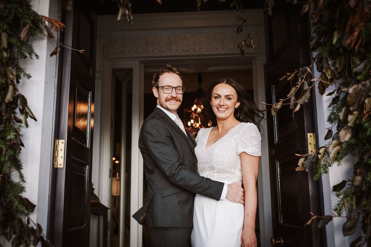 Wedding venue entrance decorated with lush greenery and natural light streaming through.