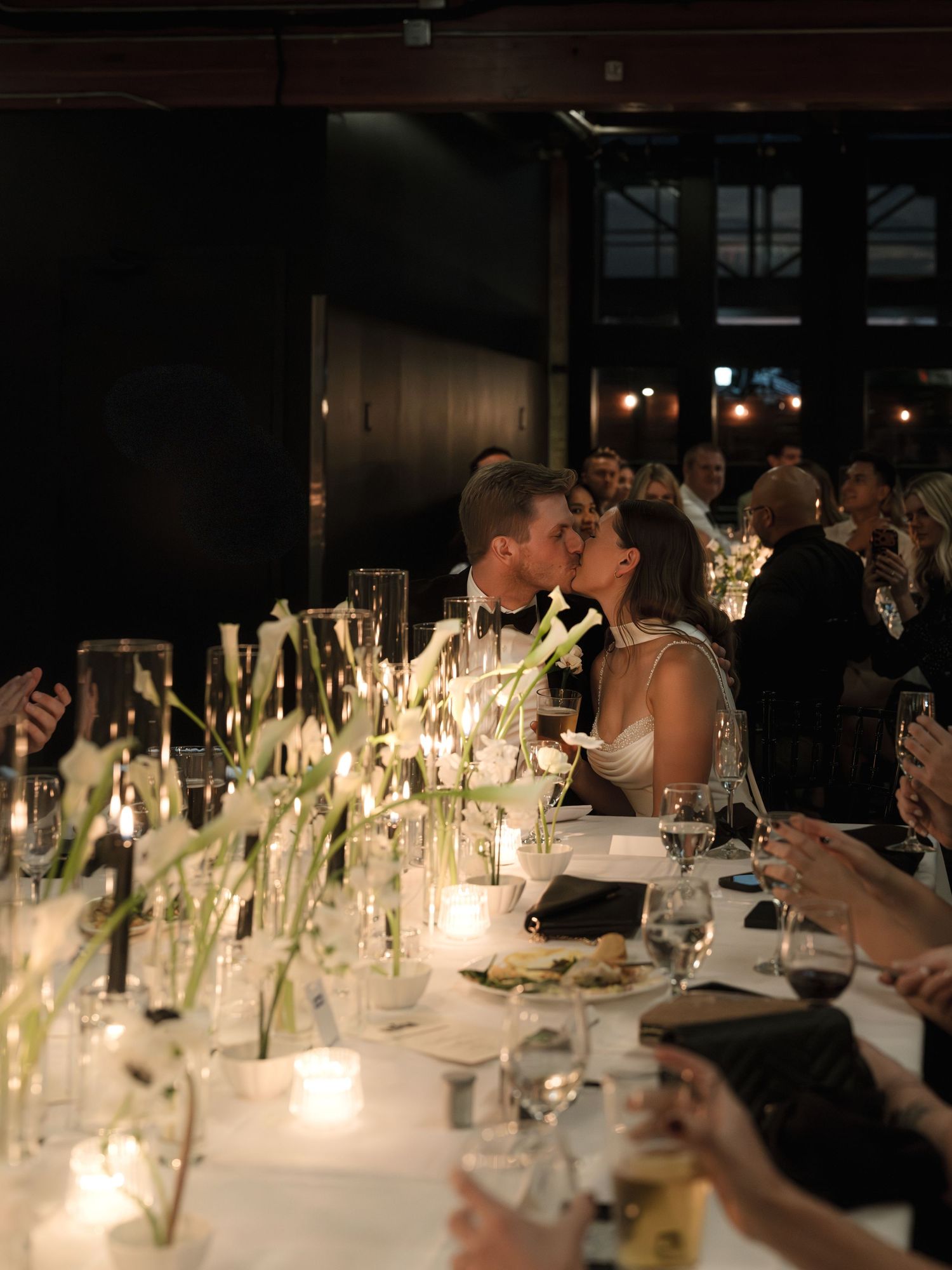 A romantic candlelit wedding reception dinner table adorned with elegant white floral centerpieces and glowing candles.