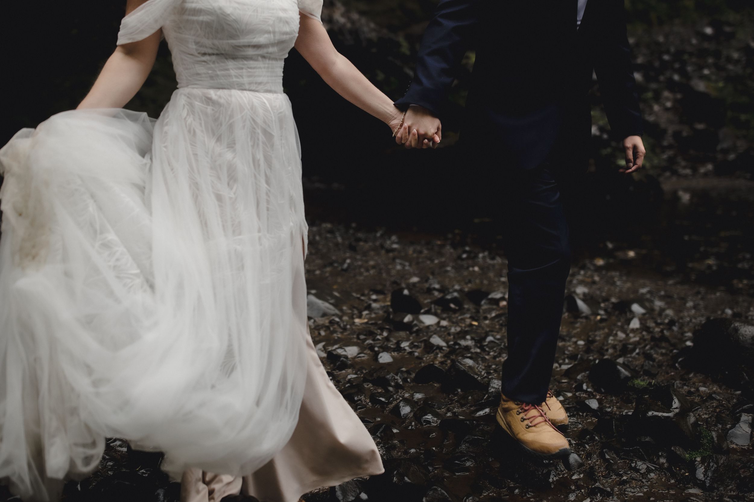A bride in a white dress twirls gracefully in a moody forest setting.