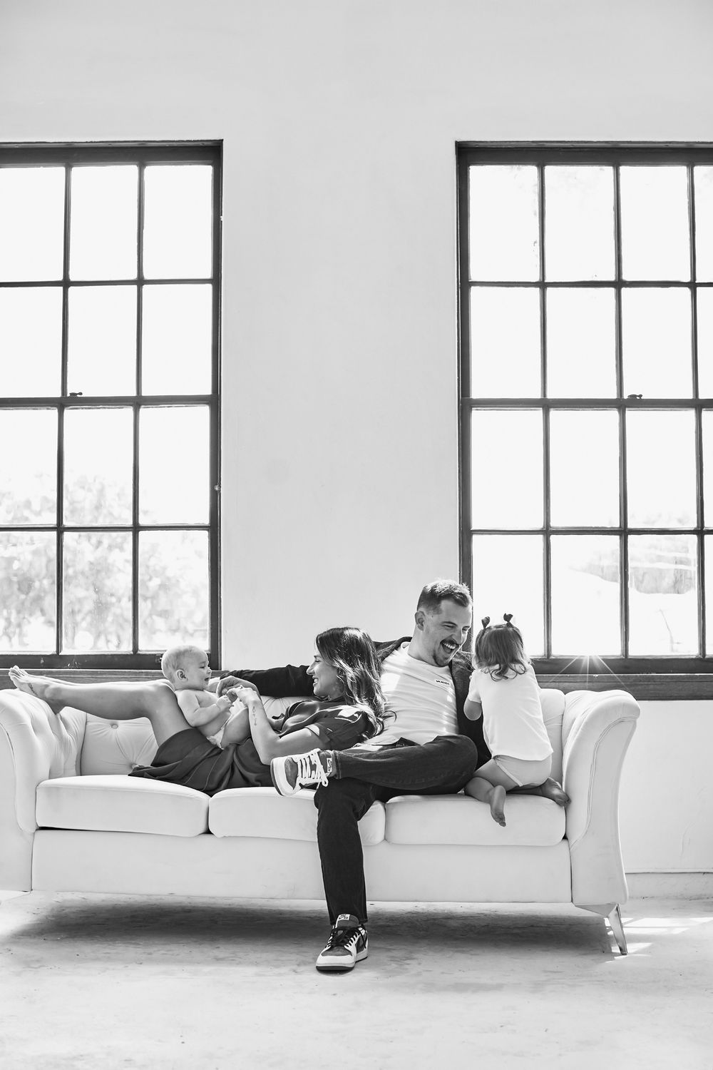 Series of poses on a white couch in a bright studio with large windows.