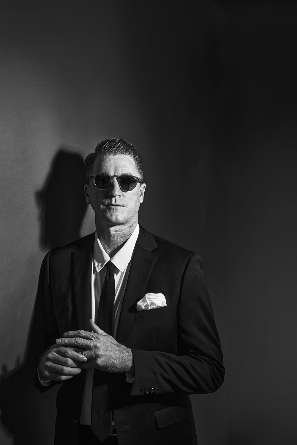 Film noir style portraits in dark lighting with sunglasses and formal attire.