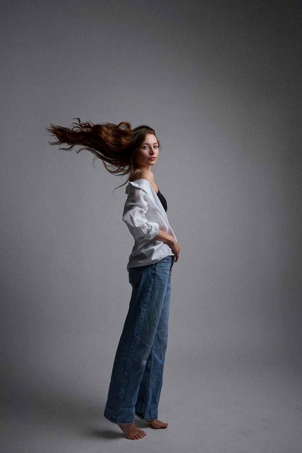 A dynamic sequence of dance movements showing a figure in jeans and white shirt against a gray backdrop.