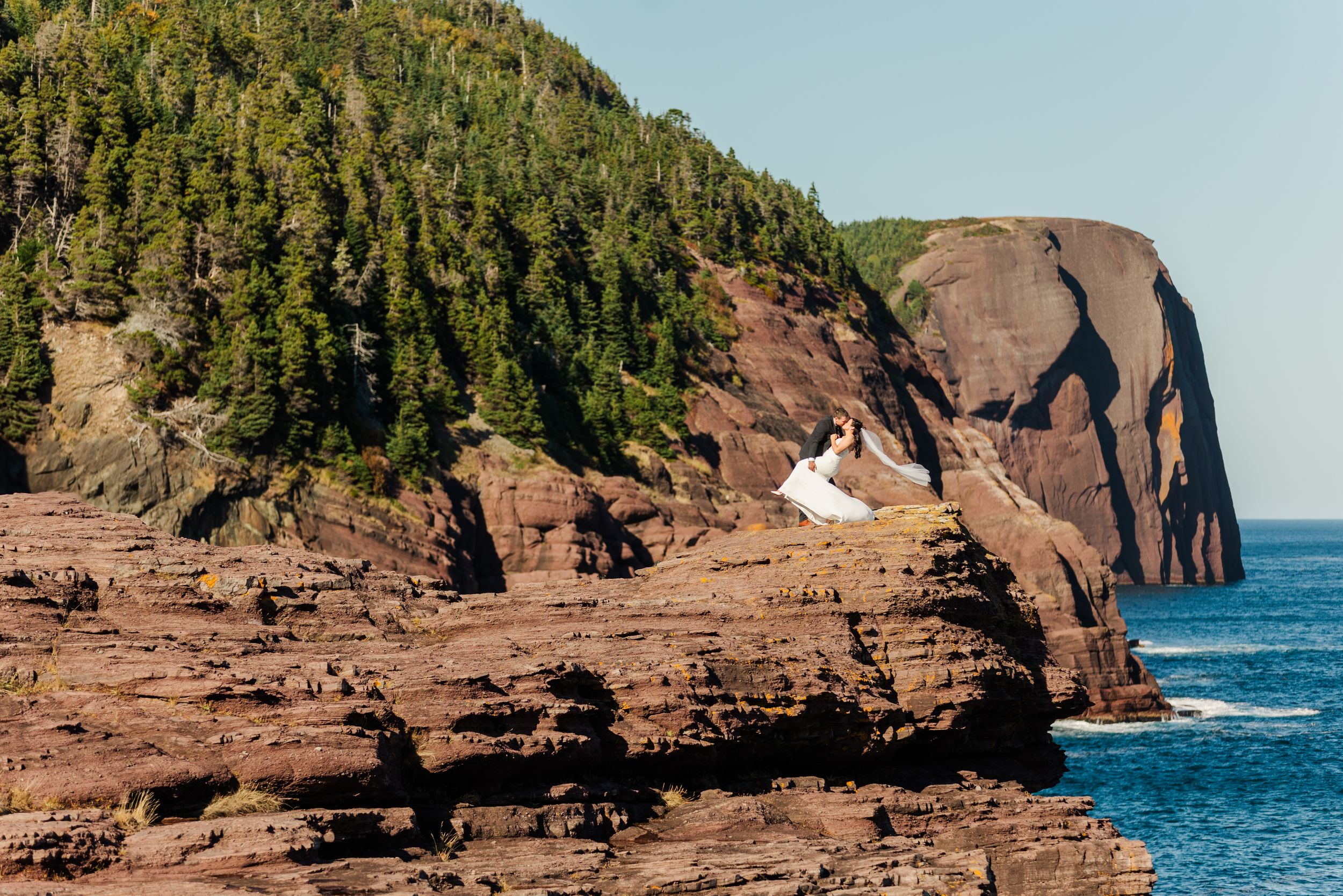 Scenic panoramic view of red sandstone cliffs along the Bay of Fundy coastline in New Brunswick at high tide.