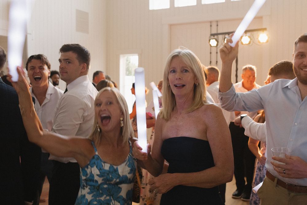 Wedding celebration with guests dancing and socializing in a bright indoor venue.