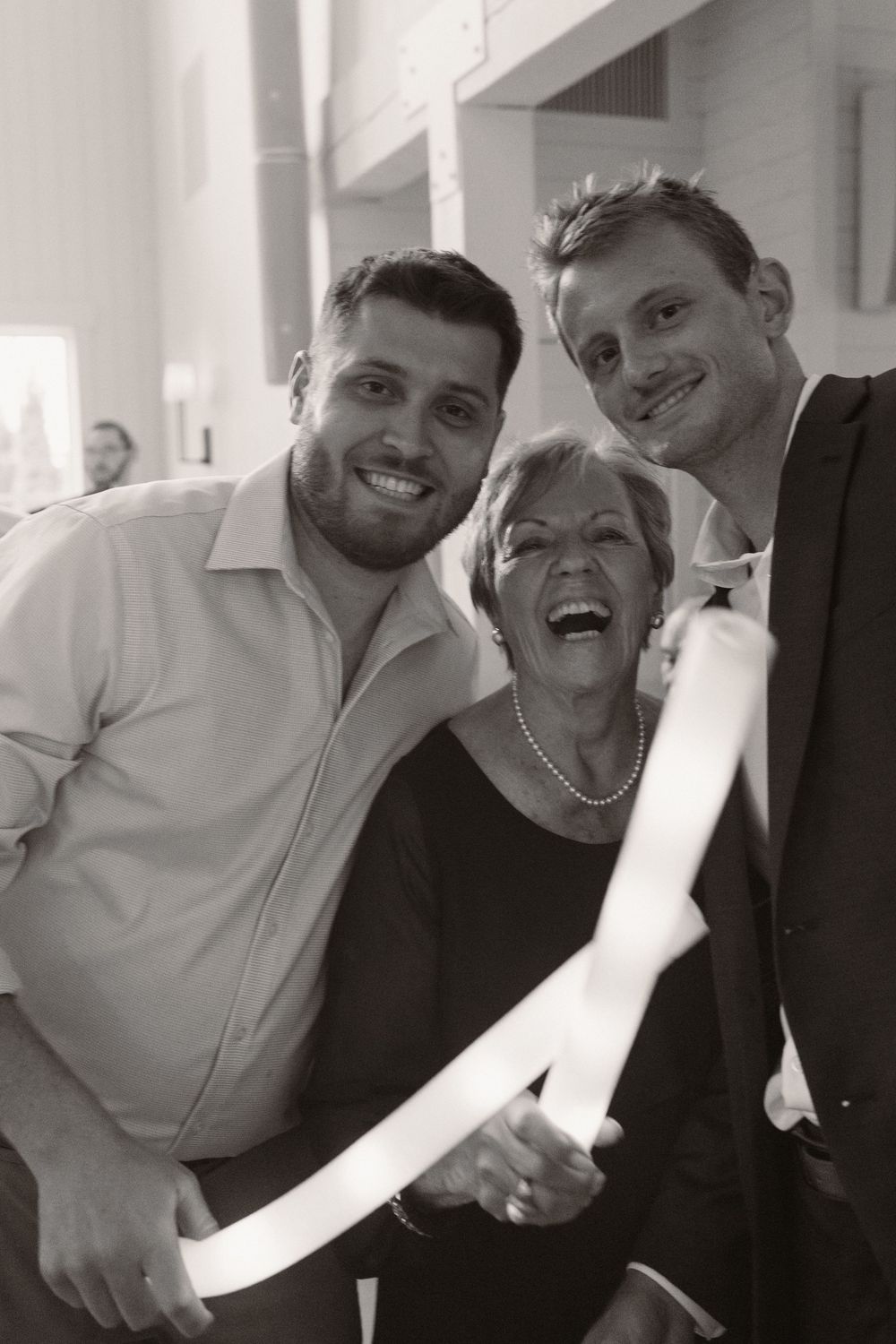 Candid black and white photo of wedding guests laughing and celebrating together.