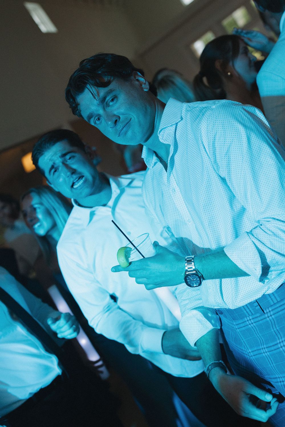 Wedding guests illuminated in blue lighting during an evening reception celebration.