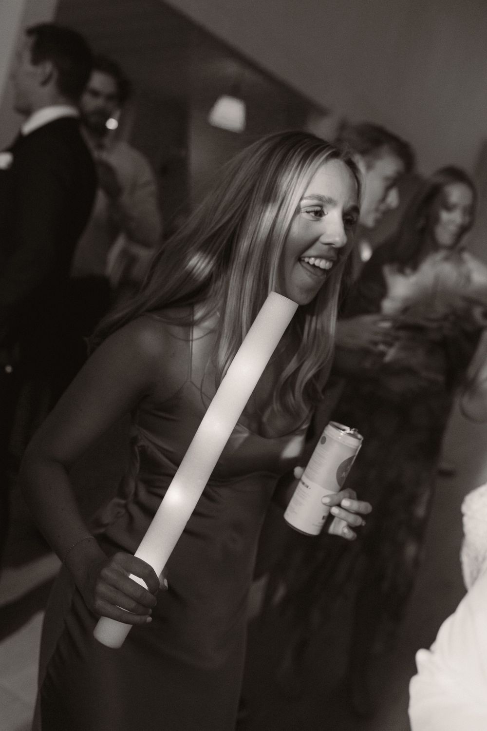 Black and white candid shot of wedding guests enjoying drinks at a reception.