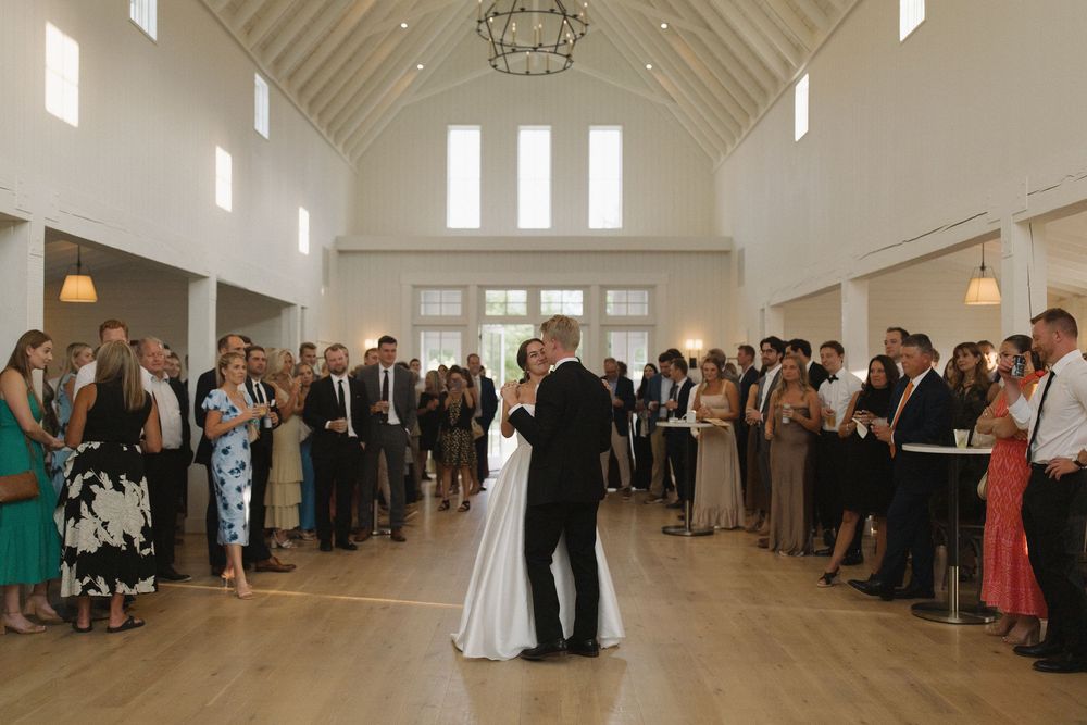 Wedding celebration in a bright white chapel with high ceilings and hanging chandeliers.