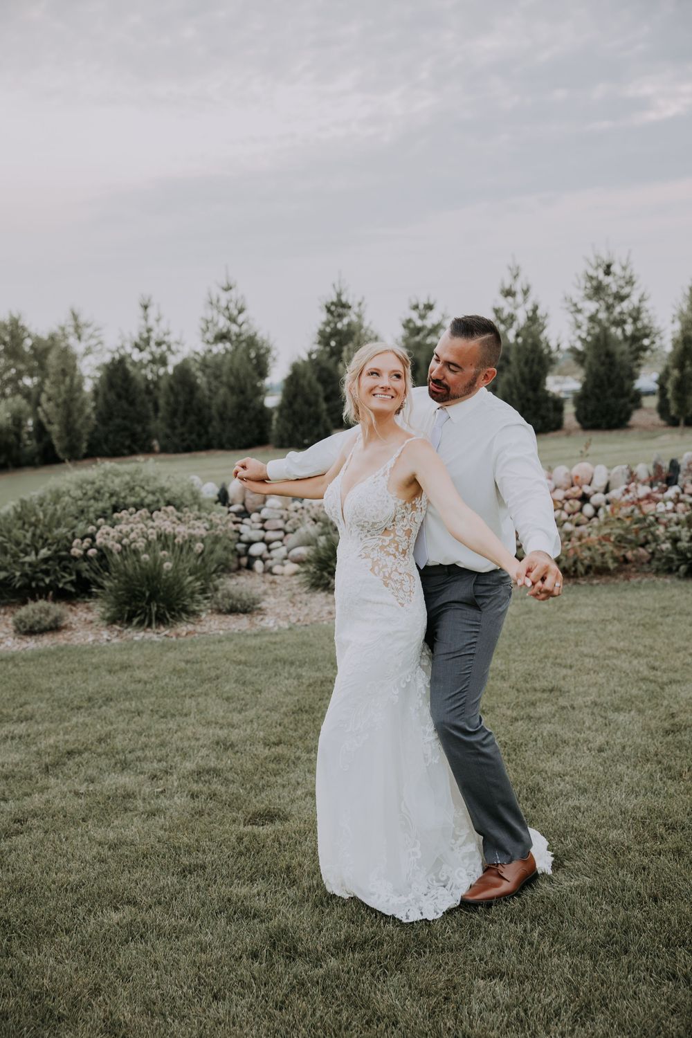 A couple dances together on a grassy lawn during their outdoor wedding celebration.