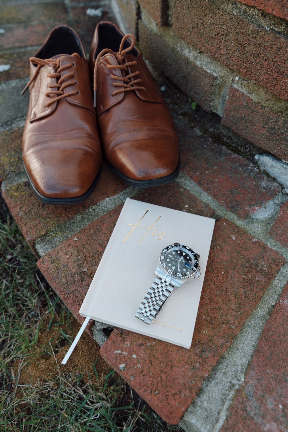 Brown leather dress shoes arranged on brick steps with cigarettes and paper napkins.