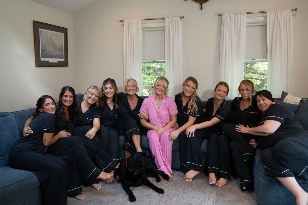 Wedding party group photo on a blue couch in a living room setting.