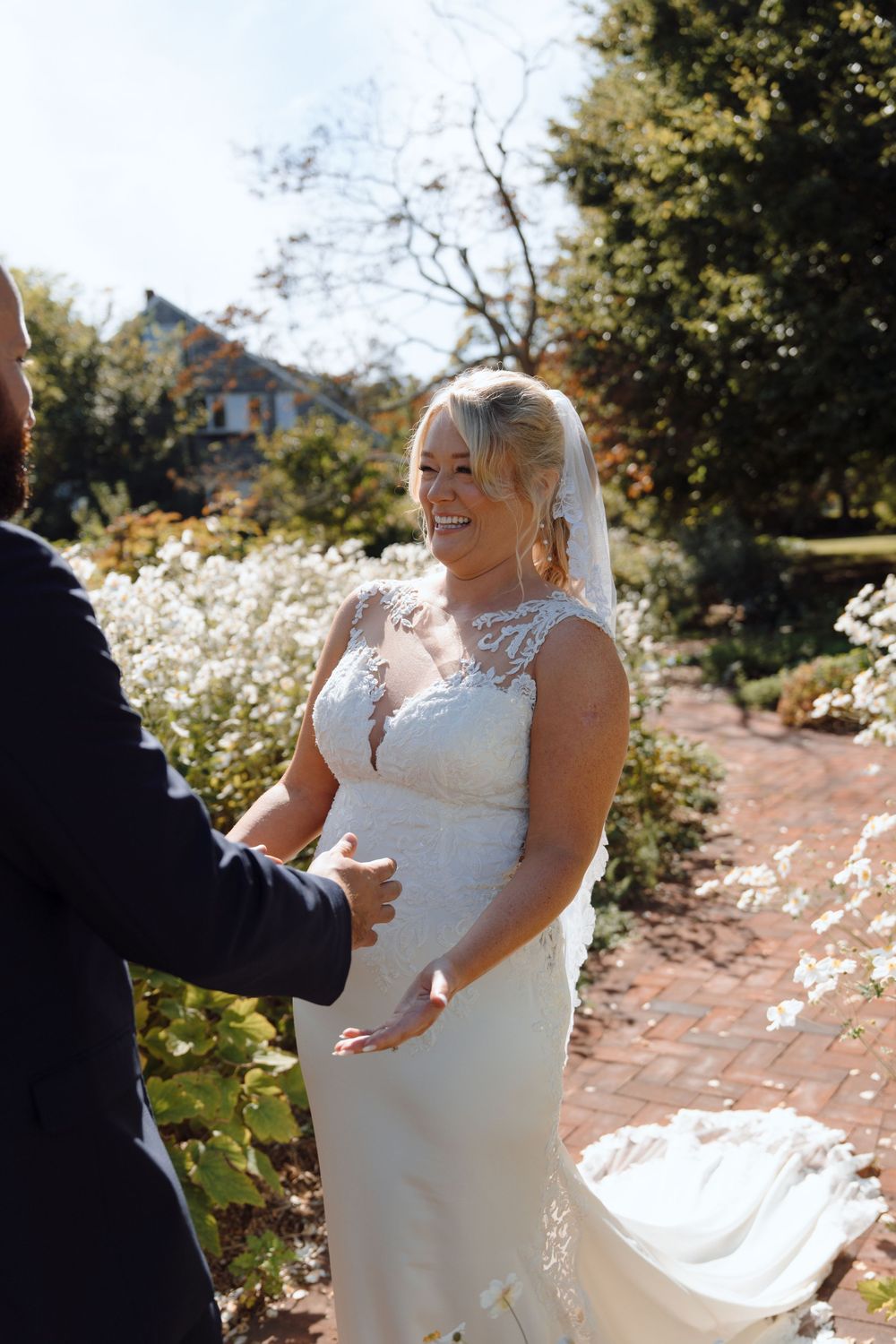 A couple shares their first look moment in a garden filled with white flowers.