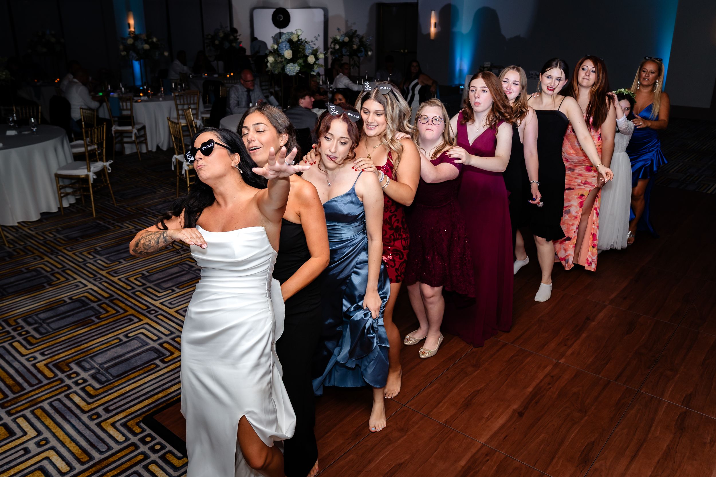 Wedding guests enjoying themselves on a dark dance floor with blue lighting effects.