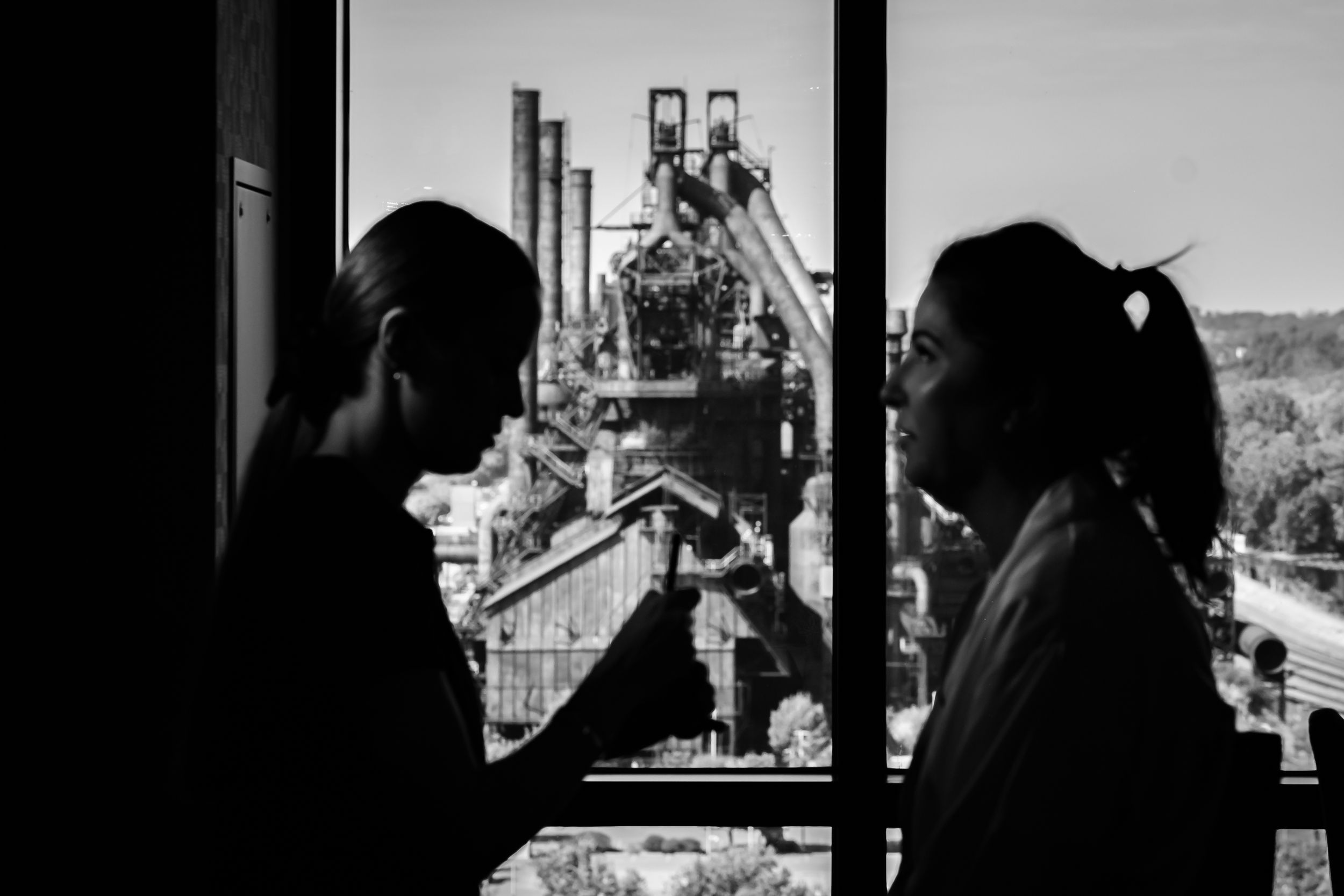 Silhouettes of people getting ready by a window during wedding preparations.