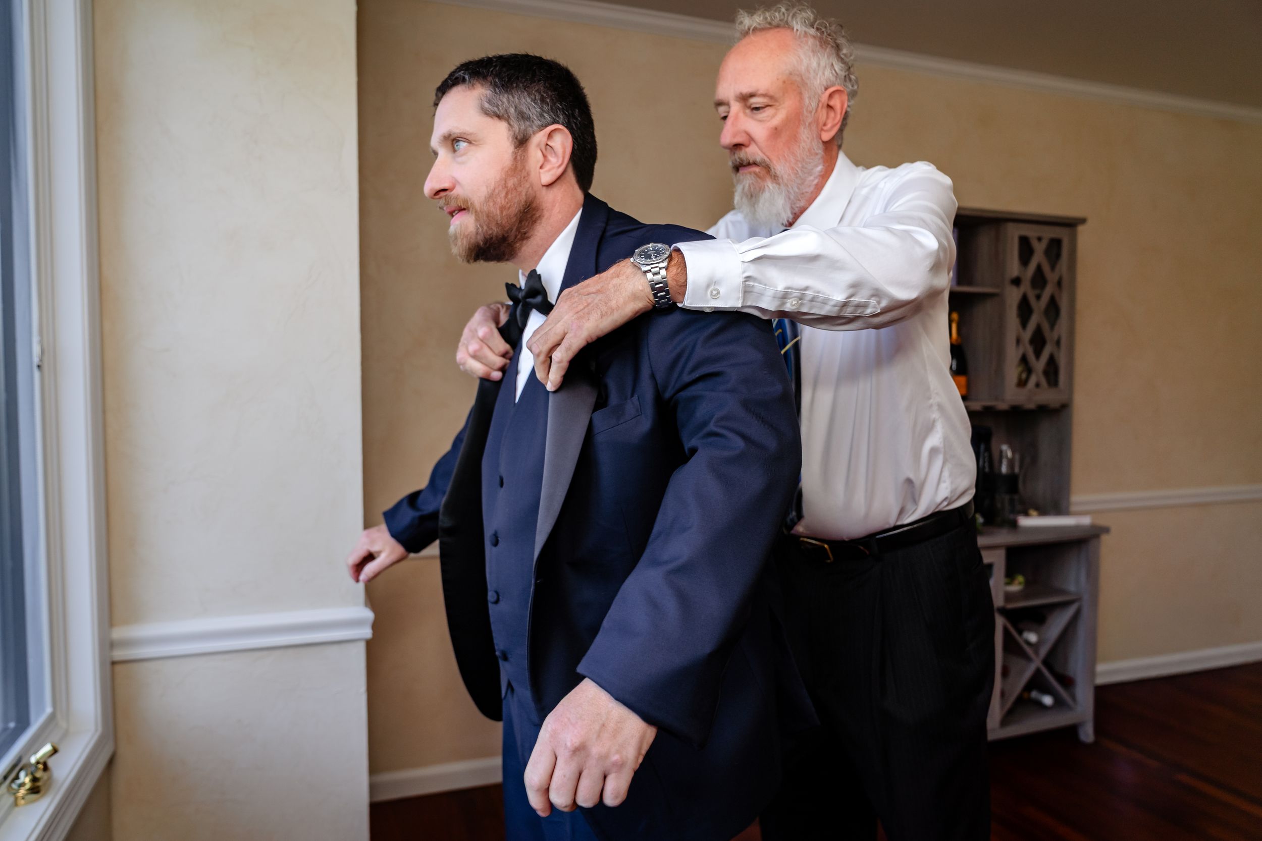 Wedding party members engage in playful interactions while dressed in formal suits and ties.