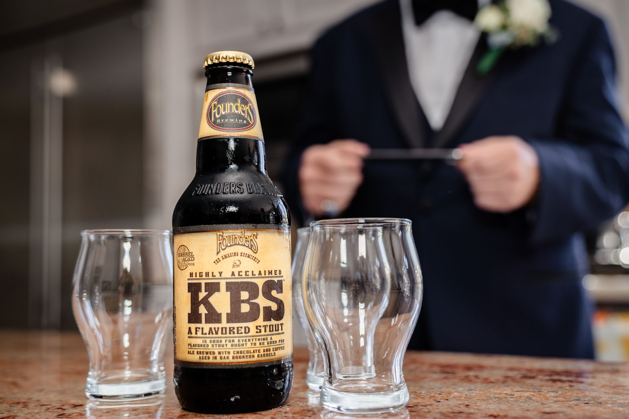 Craft beer bottles and glasses arranged on a wooden surface during pre-wedding celebrations.