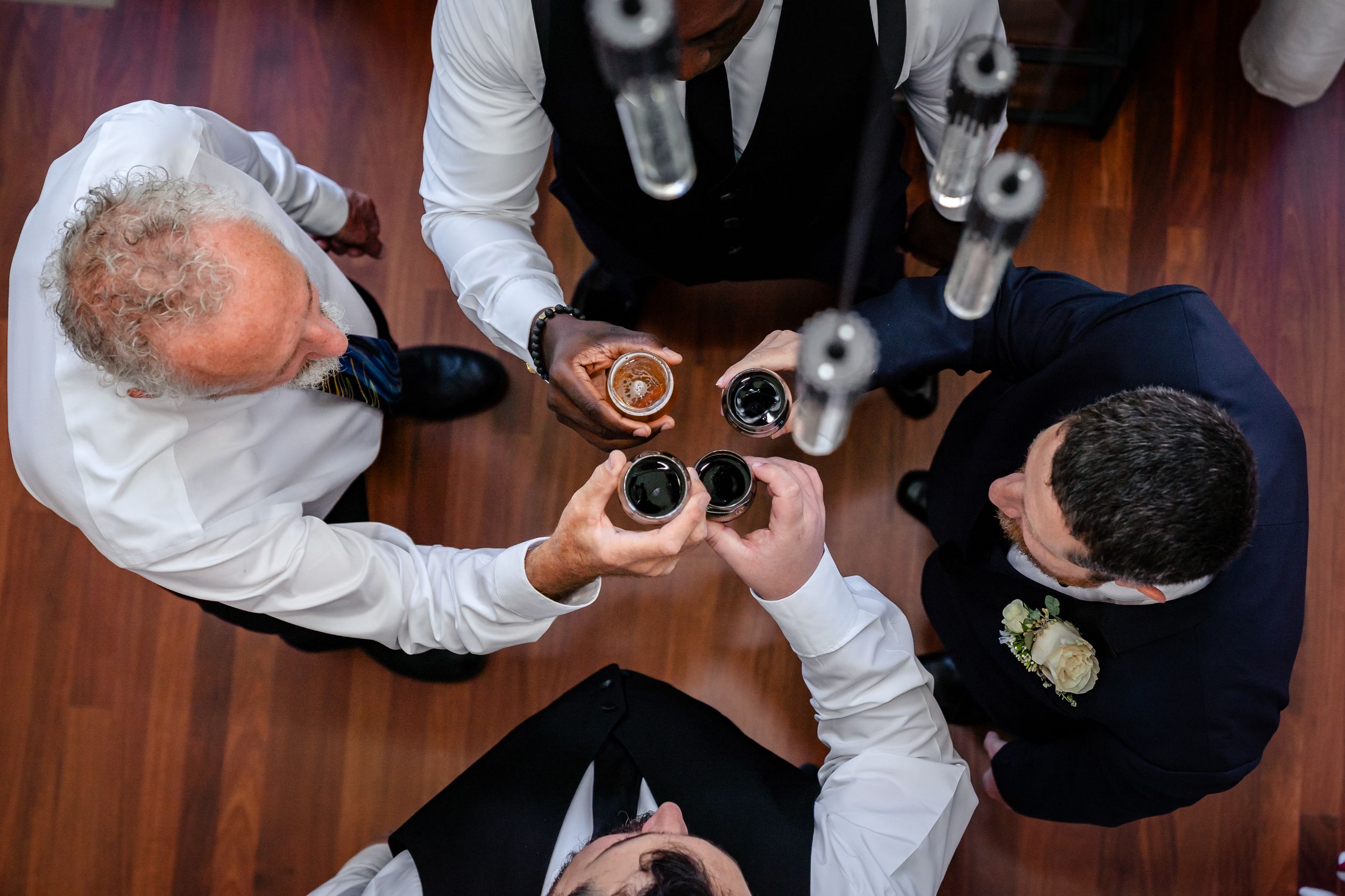 Overhead view of formal-dressed attendees sharing drinks at a wooden table.