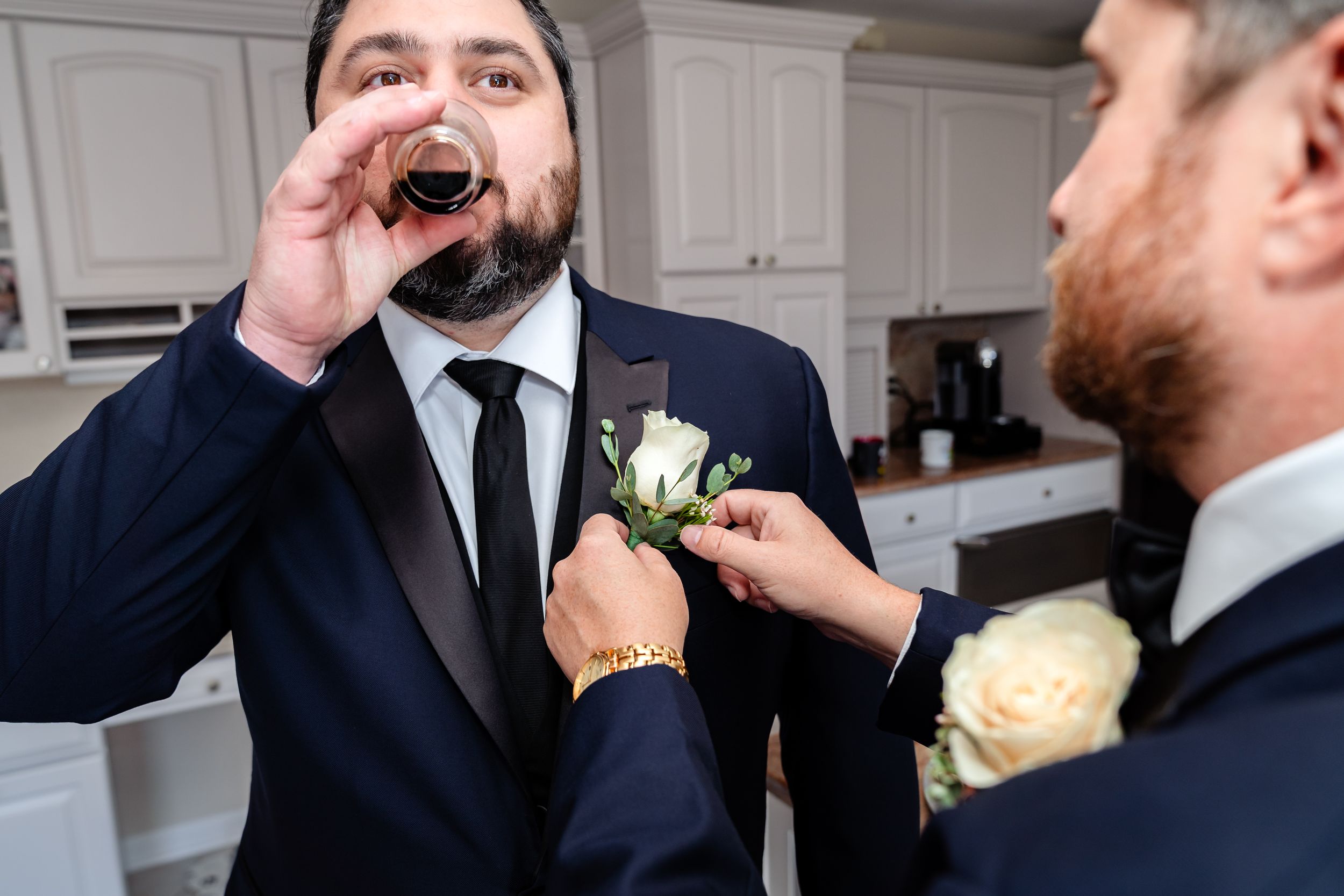 Groomsmen in dark suits and boutonnieres prepare for wedding festivities.