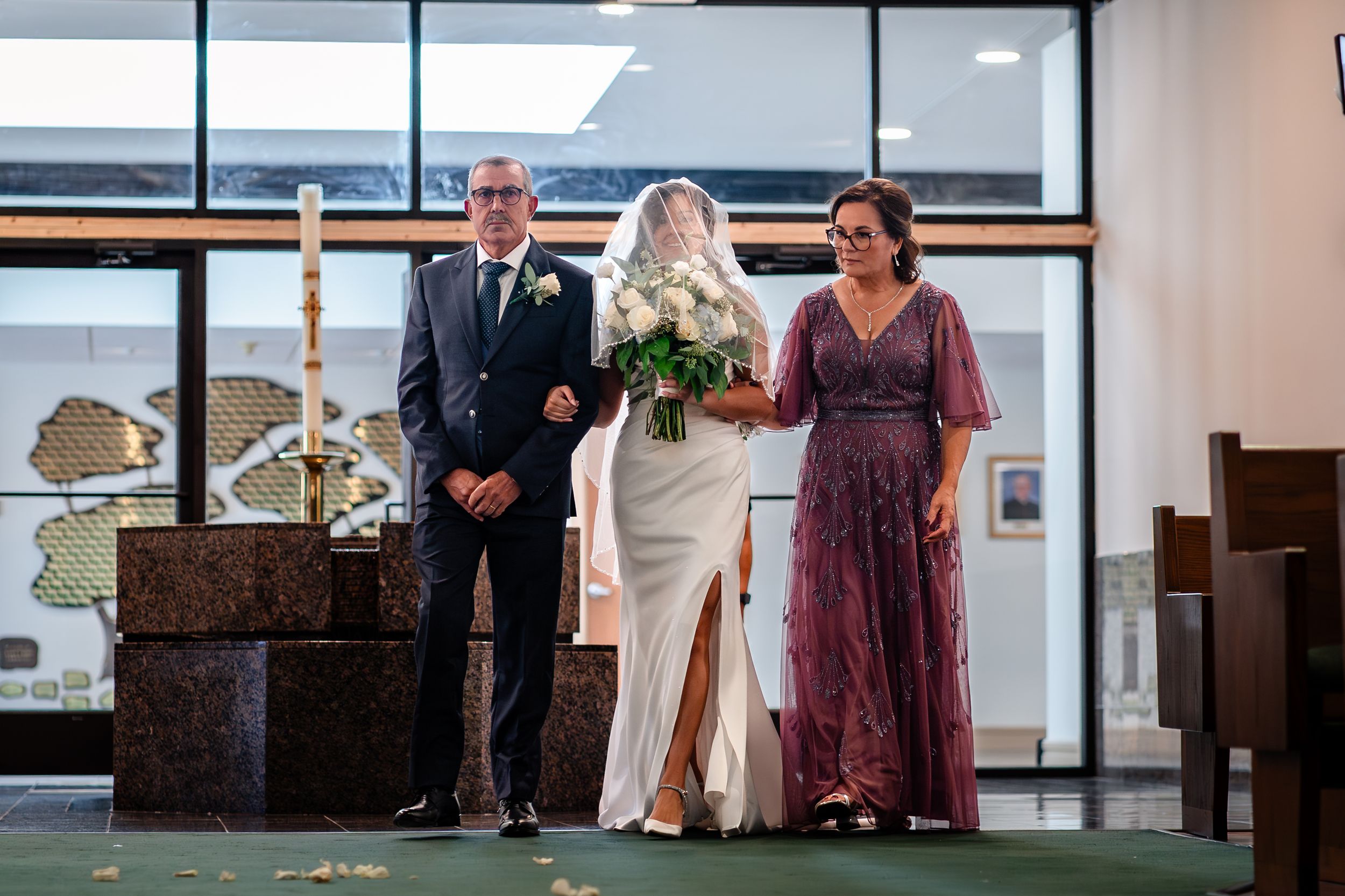 Wedding ceremony taking place in a modern church sanctuary with large windows.