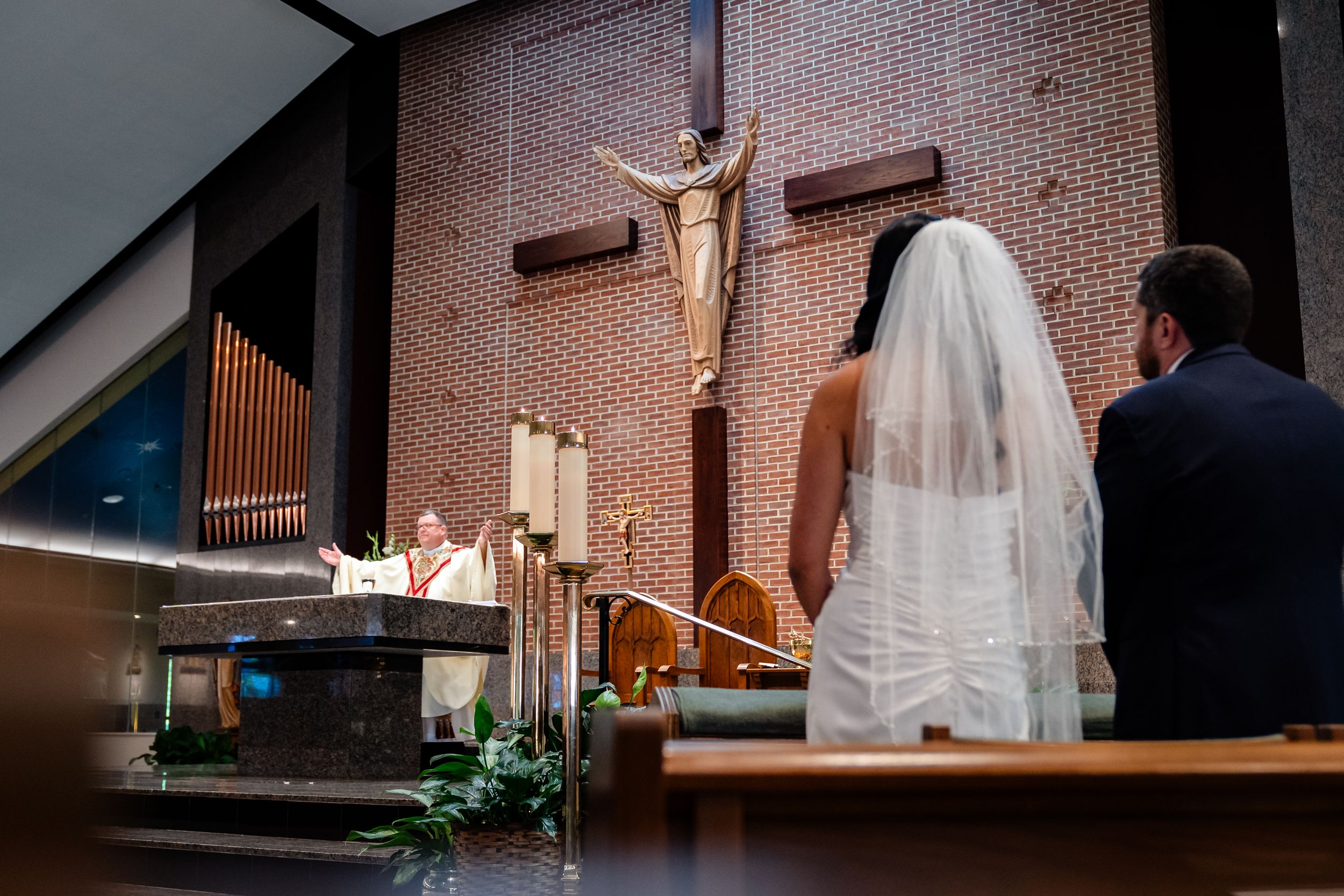 Wedding ceremony in a brick church with sunlight streaming through stained glass windows.