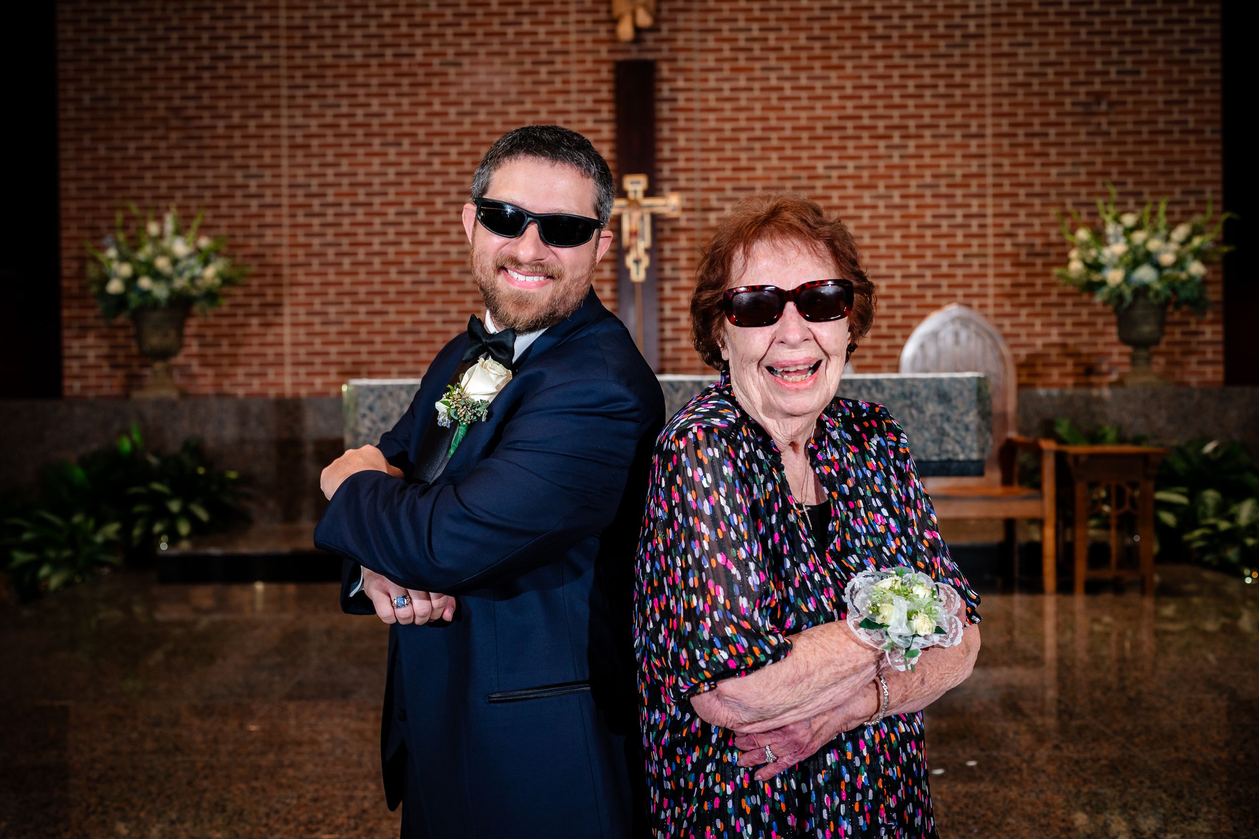 Wedding guests sharing hugs and smiles outside brick church building.