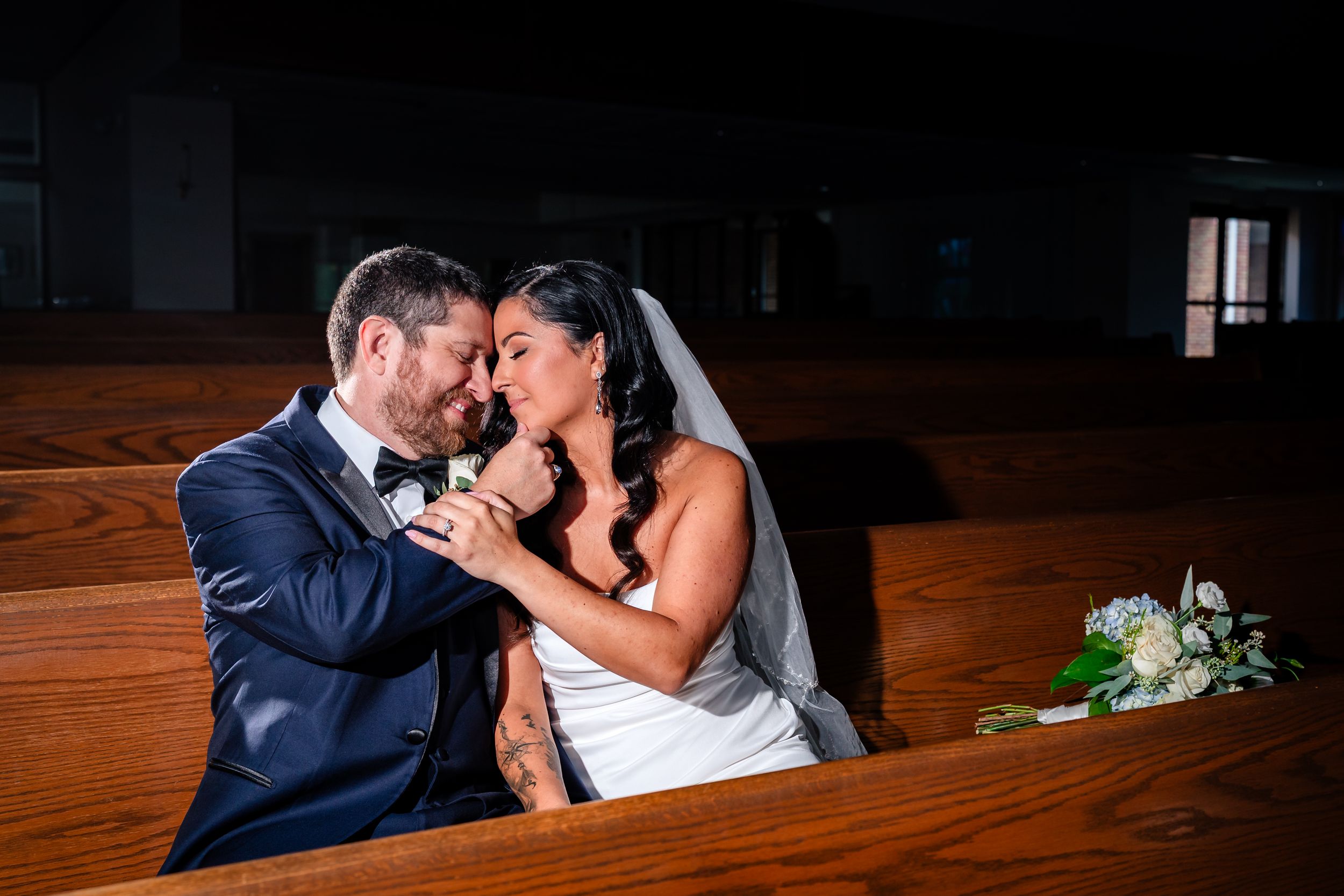 Intimate wedding couple moment captured in warm wooden church interior.