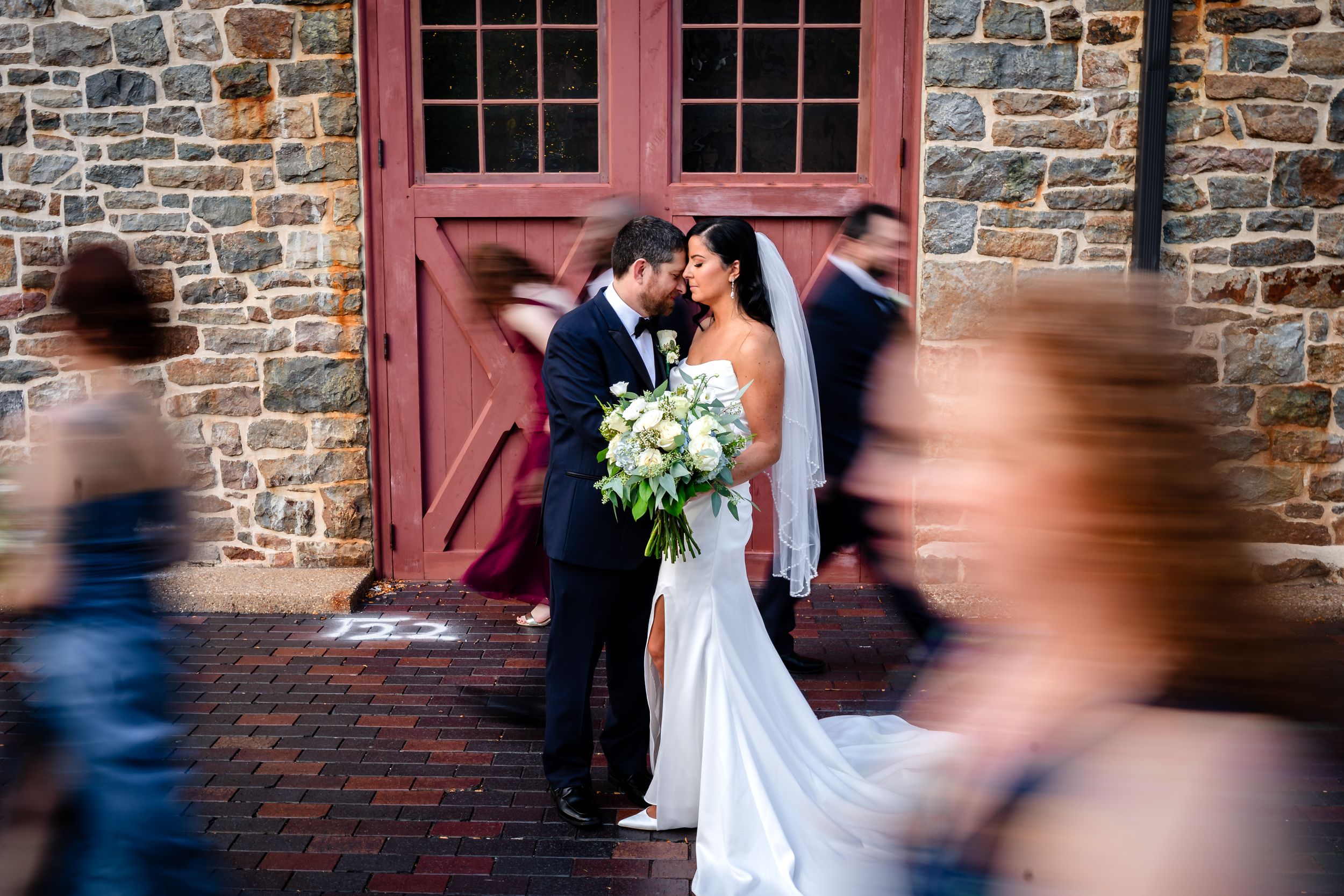 A romantic wedding moment captured through a decorative iron gate against a rustic stone wall.