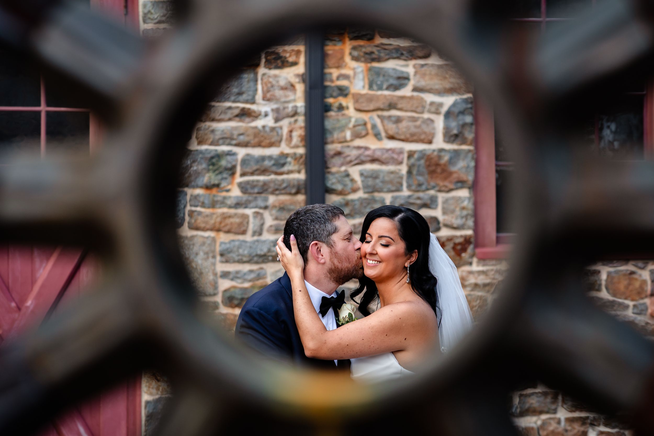 Intimate wedding scene framed through ornate metalwork against stone architecture.