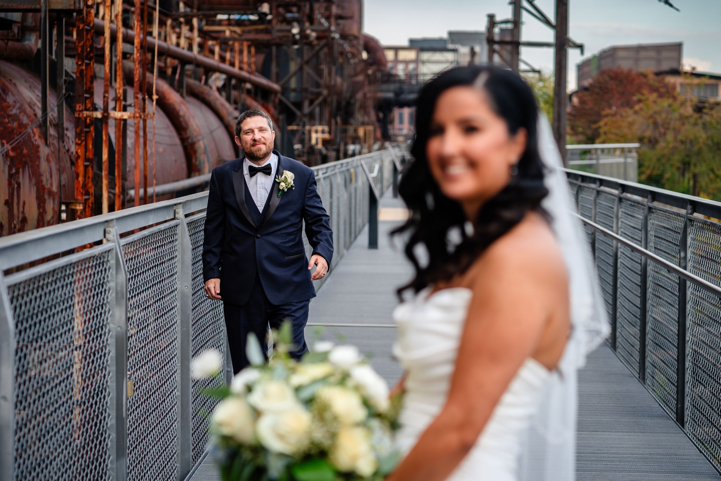 A couple shares intimate moments on an industrial bridge walkway.