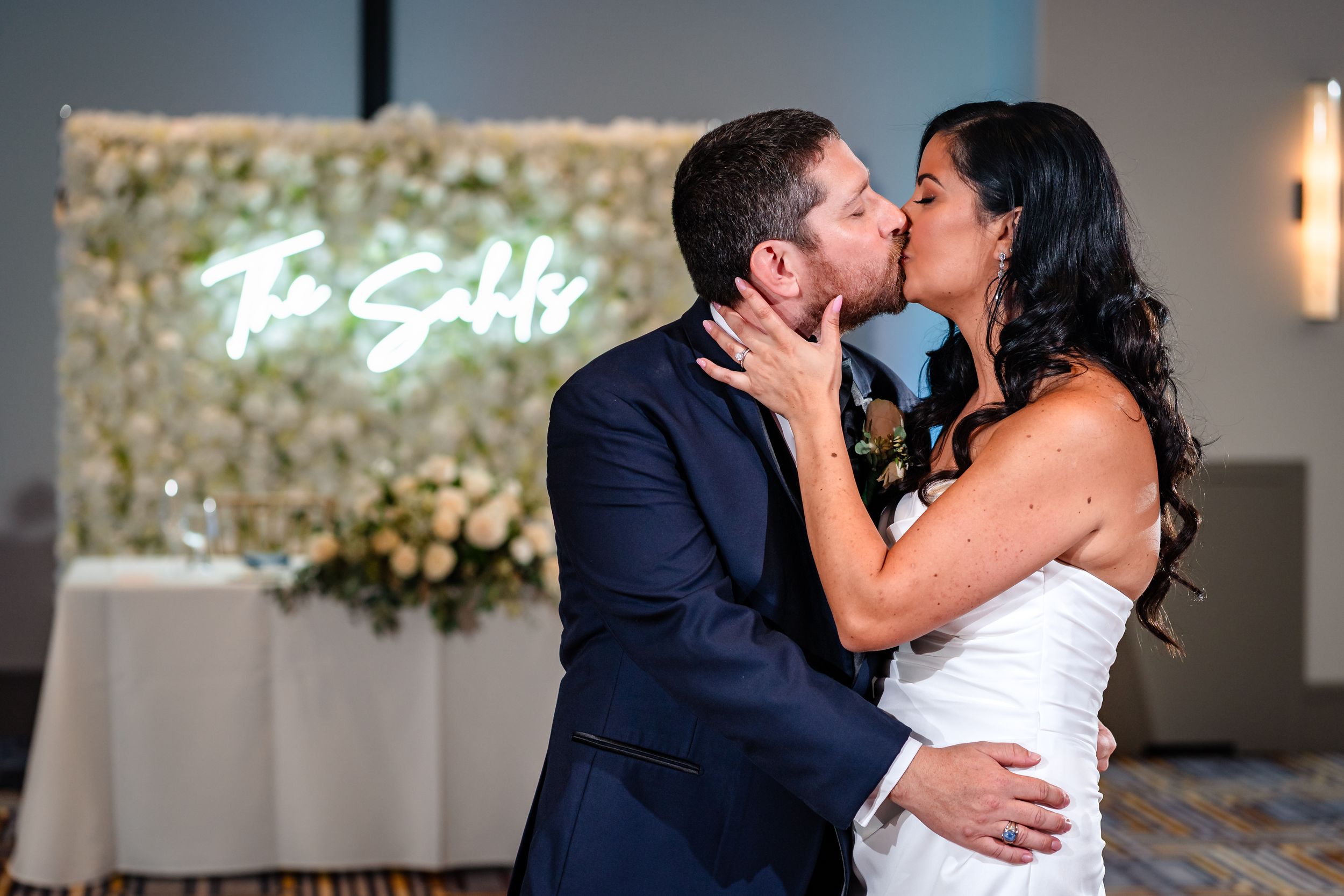 A couple shares an intimate kiss in an elegantly decorated wedding venue.