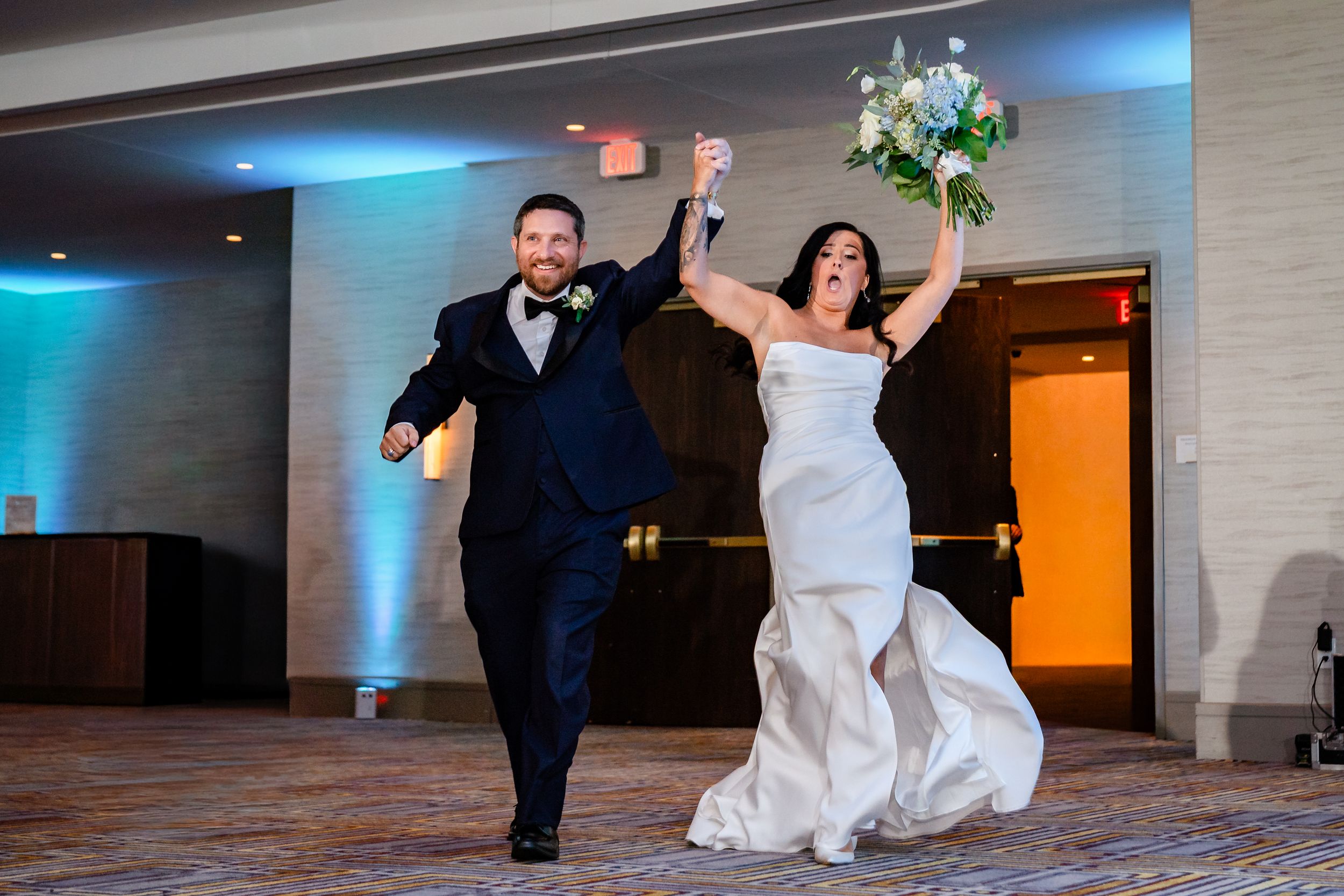 Wedding reception dancers twirl and spin on a modern dance floor with ambient blue lighting.