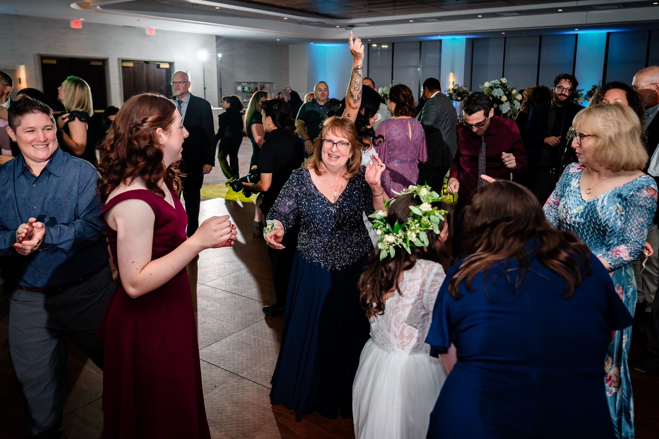Large group of wedding guests dancing and celebrating on a crowded dance floor.