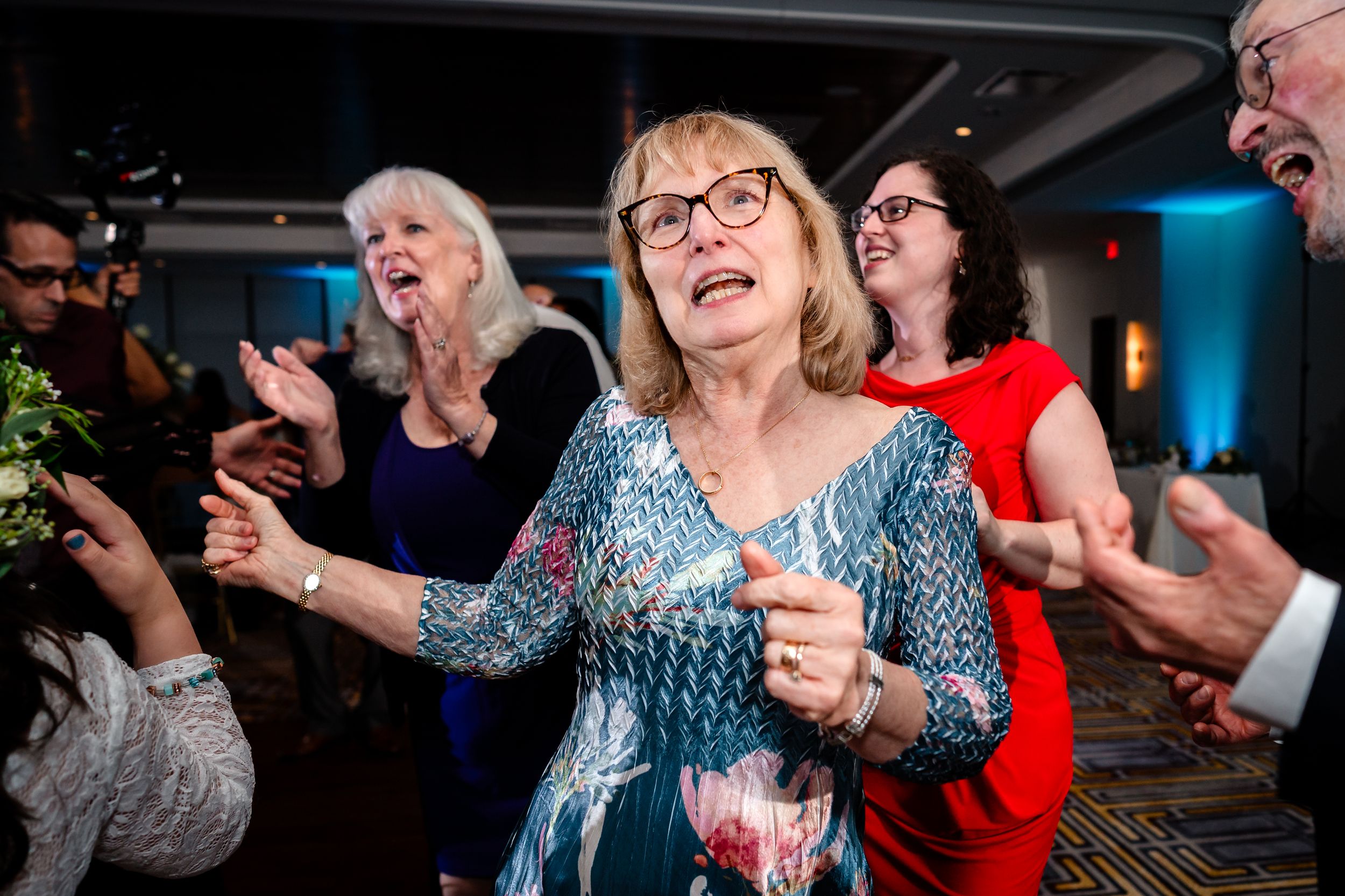 Wedding guests laughing and dancing together during an energetic reception party.