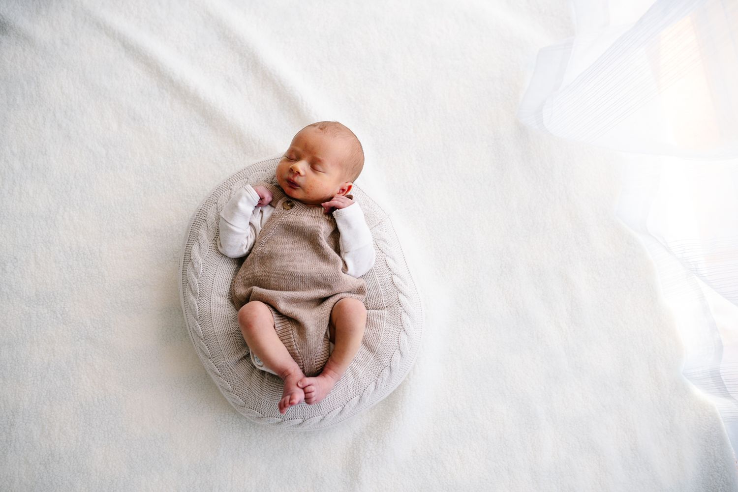 A newborn baby lies on soft white fabric in multiple artistic poses for a professional newborn photo shoot in Melbourne.