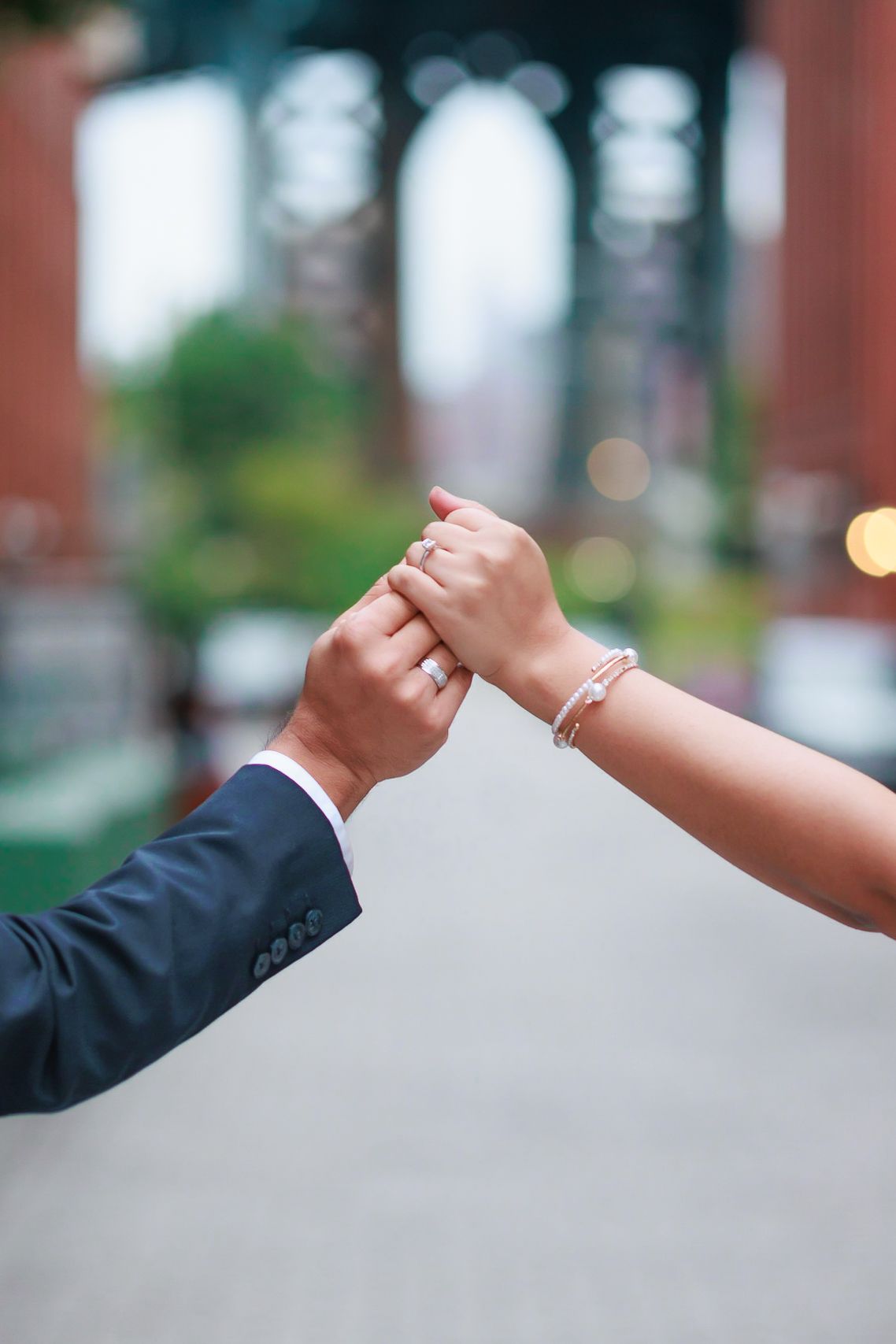 Close up of engaged couple holding hands showing engagement ring.